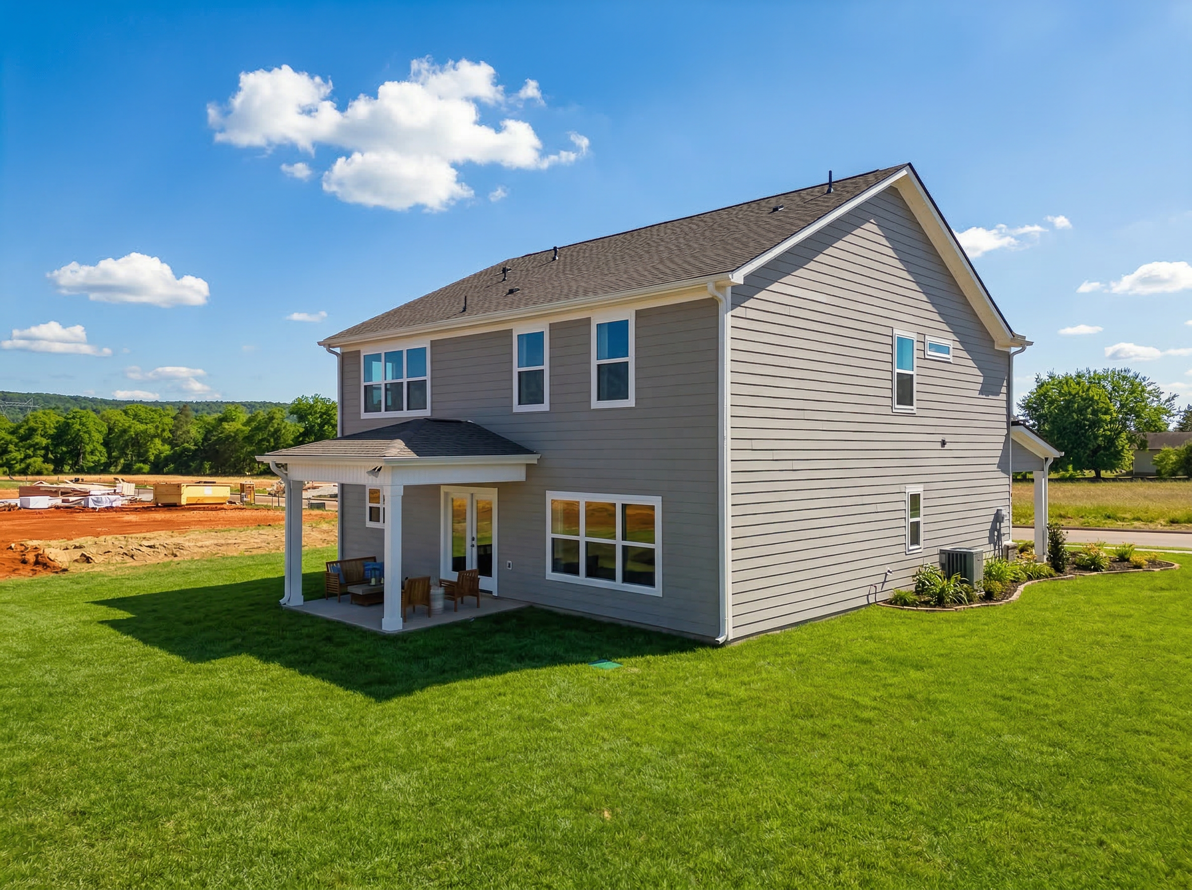 Gray-sided two-story home with covered front porch and green lawn at Berry Cove in New Market, Alabama