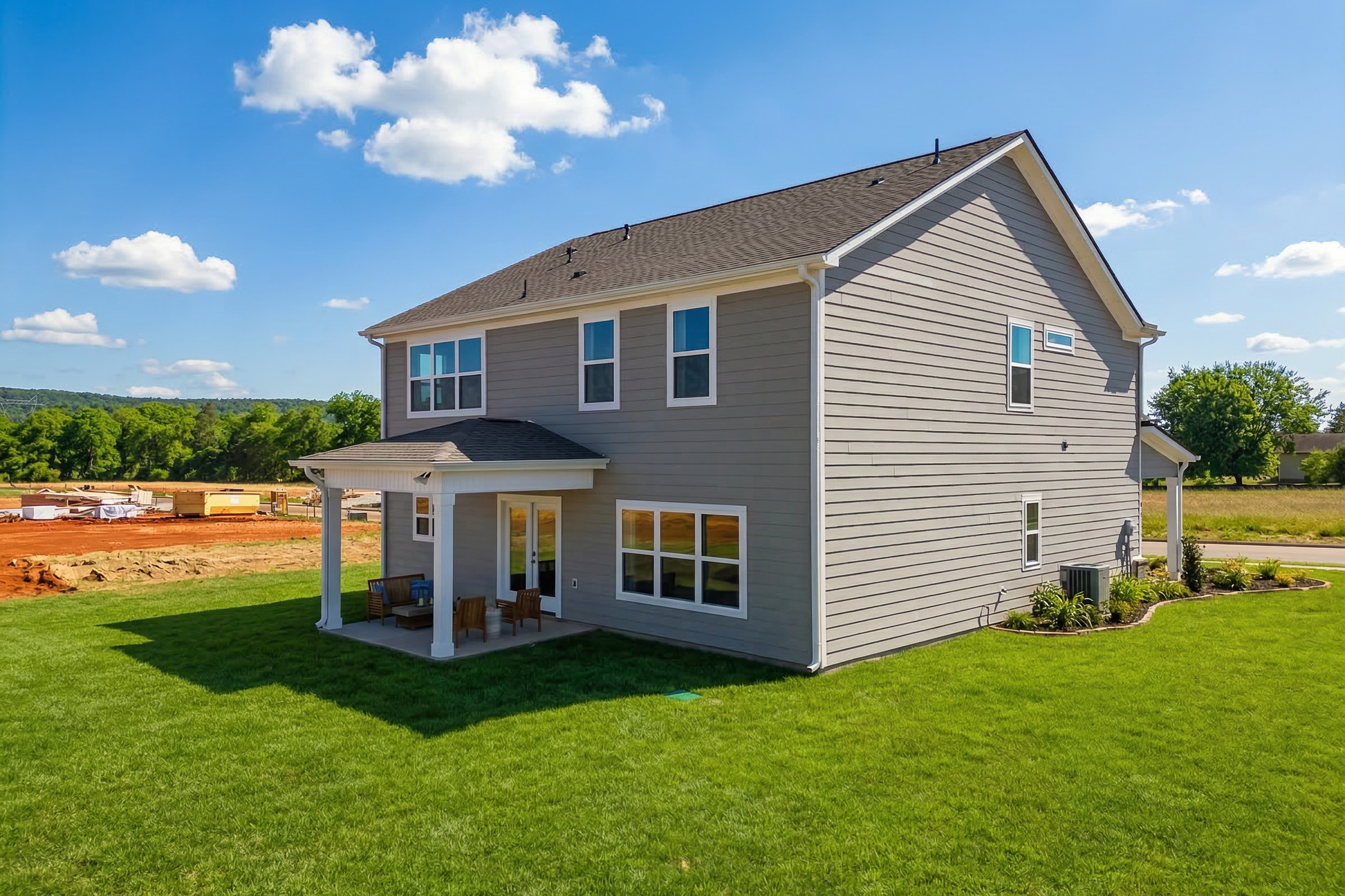 Gray-sided two-story home with covered front porch and green lawn at Berry Cove in New Market, Alabama