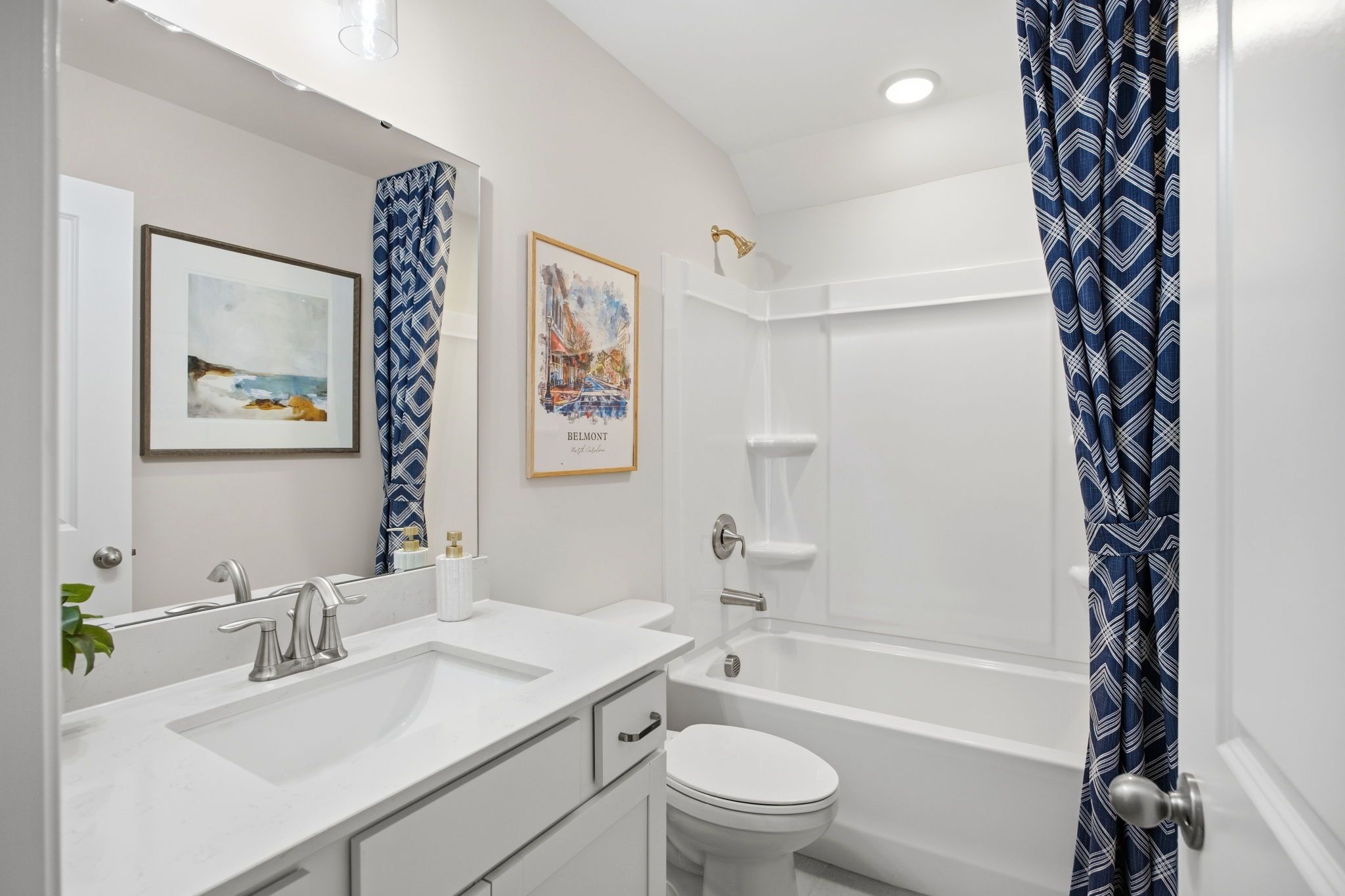 Spacious bathroom at Enclave at Belmont in Belmont NC with white vanity, soaking tub, blue geometric shower curtain