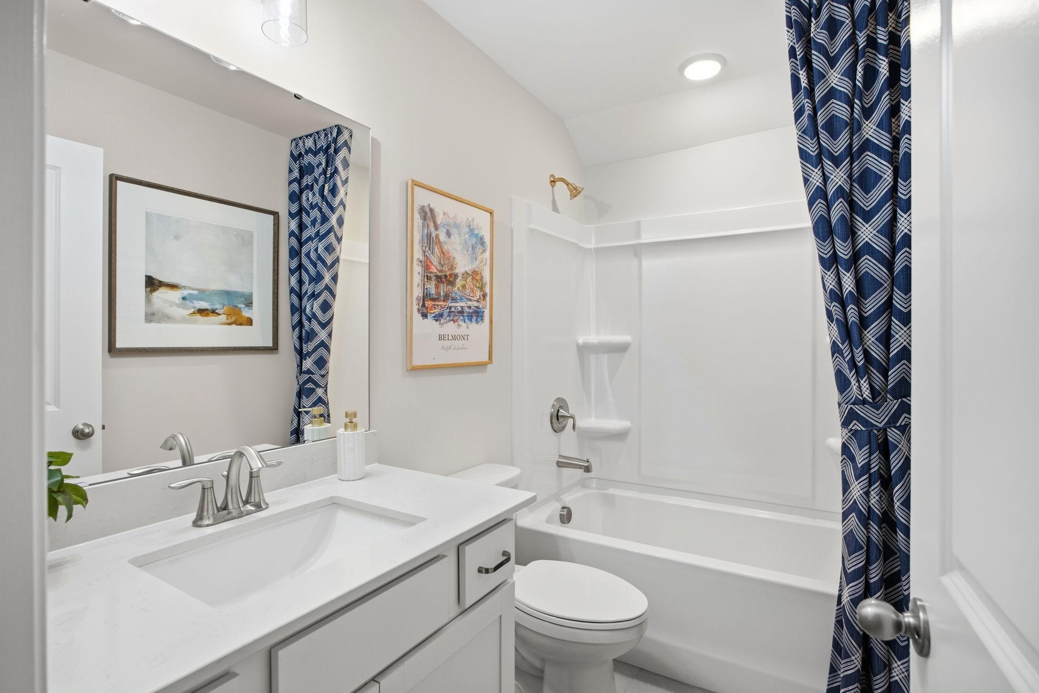 Spacious bathroom at Enclave at Belmont in Belmont NC with white vanity, soaking tub, blue geometric shower curtain