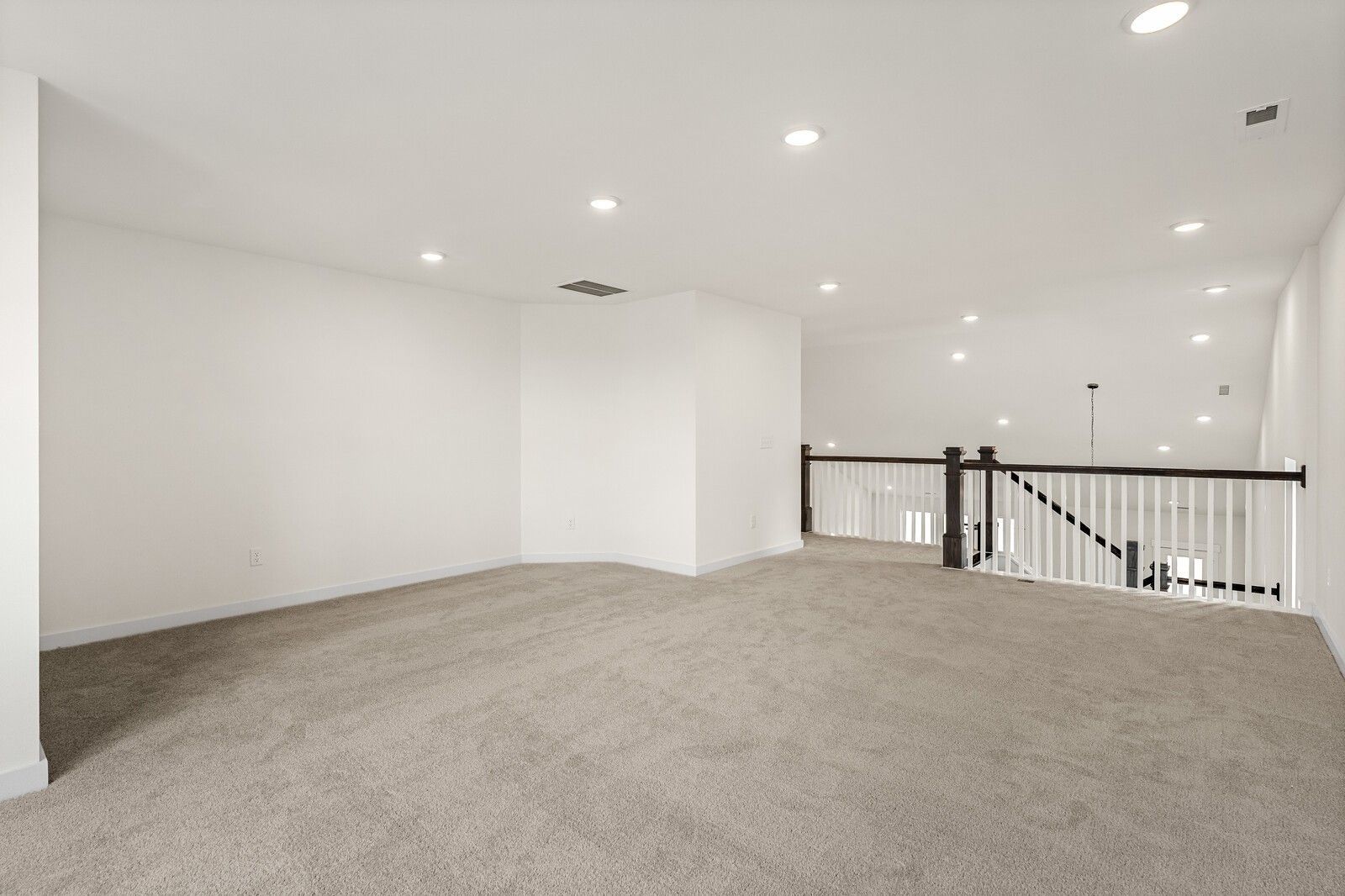 Spacious upstairs loft with beige carpet, white walls, recessed lights, and dark wood railing overlook in The Ridgeport D home, Mt. Juliet