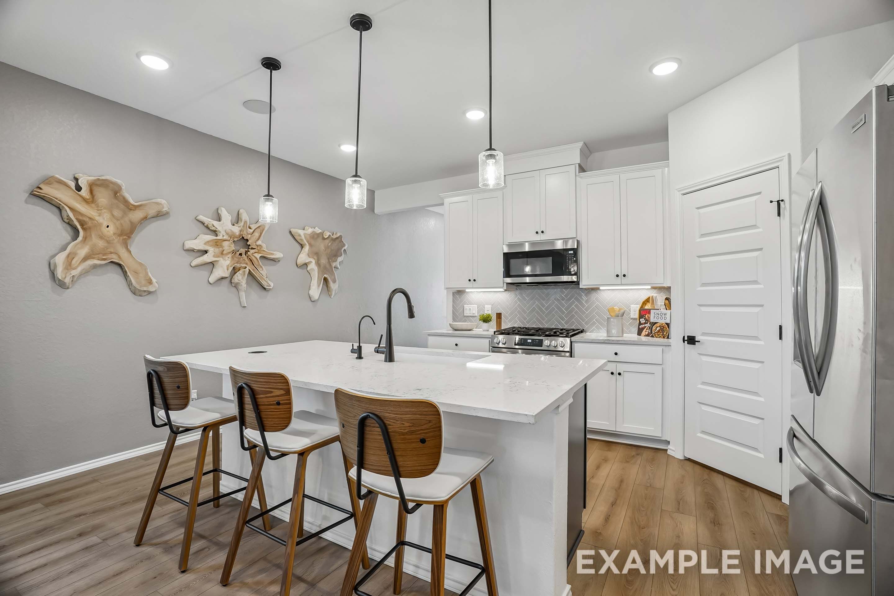 Modern kitchen in The Pinecrest D design featuring white cabinetry, quartz island, and stylish wood wall decor.