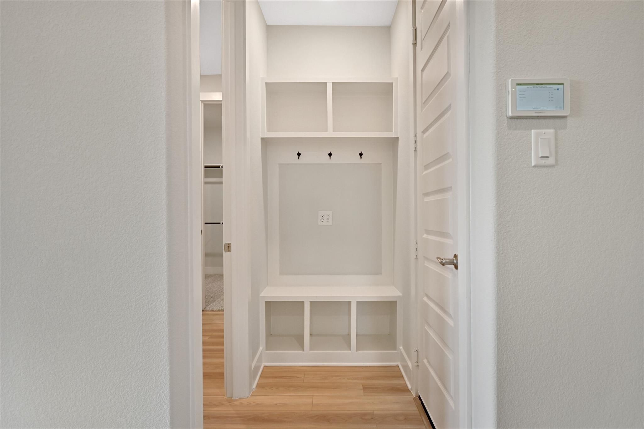 Spacious mudroom with built-in white shelves, coat hooks, bench in Davidson Homes The Edward A, Lago Mar, Texas City