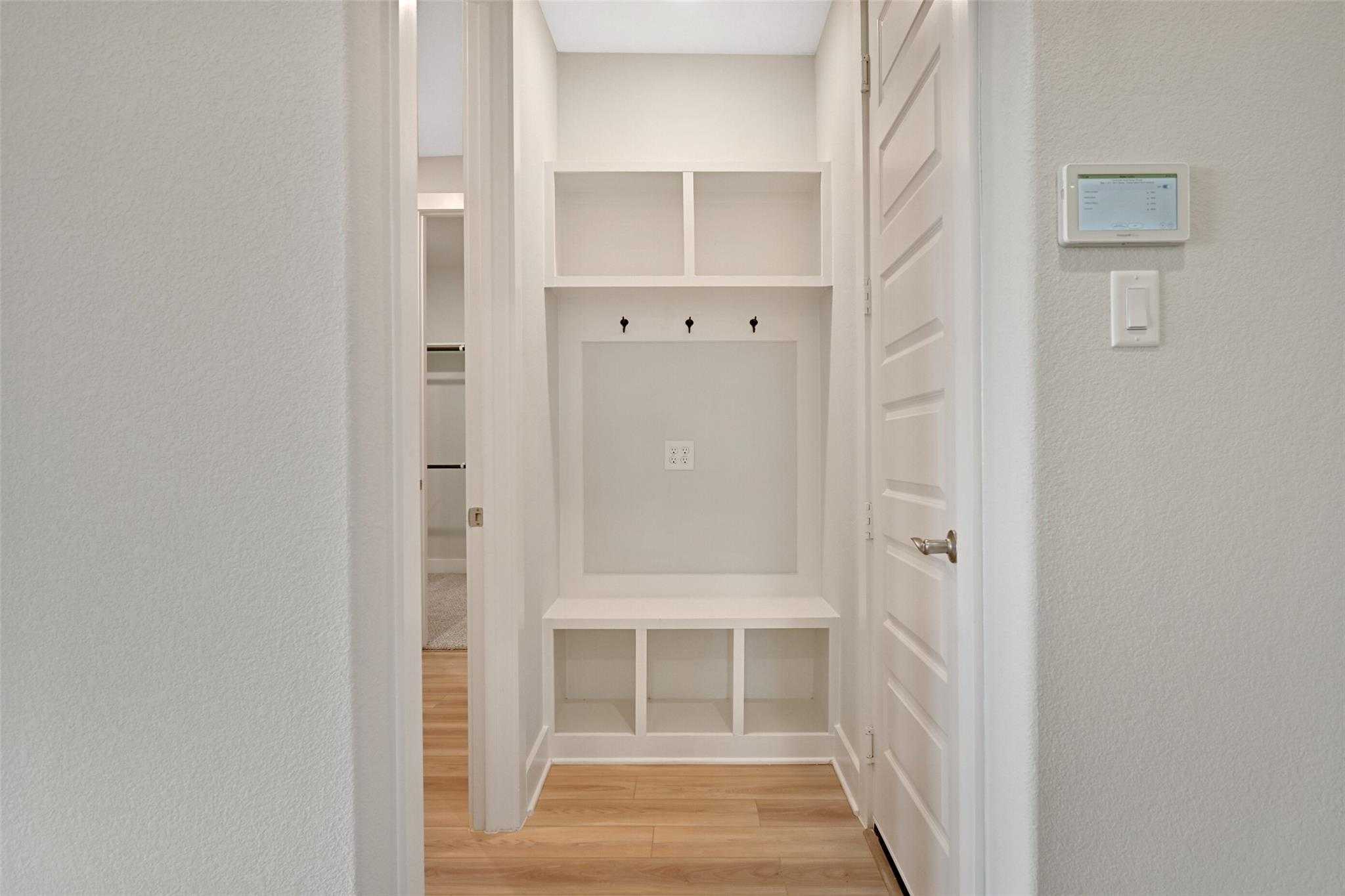 Spacious mudroom with built-in white shelves, coat hooks, bench in Davidson Homes The Edward A, Lago Mar, Texas City