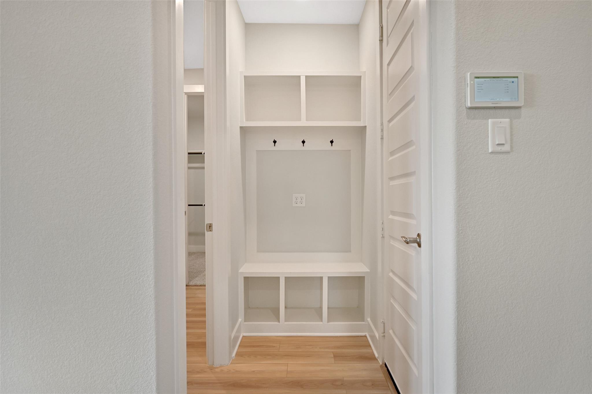Spacious mudroom with built-in white shelves, coat hooks, bench in Davidson Homes The Edward A, Lago Mar, Texas City