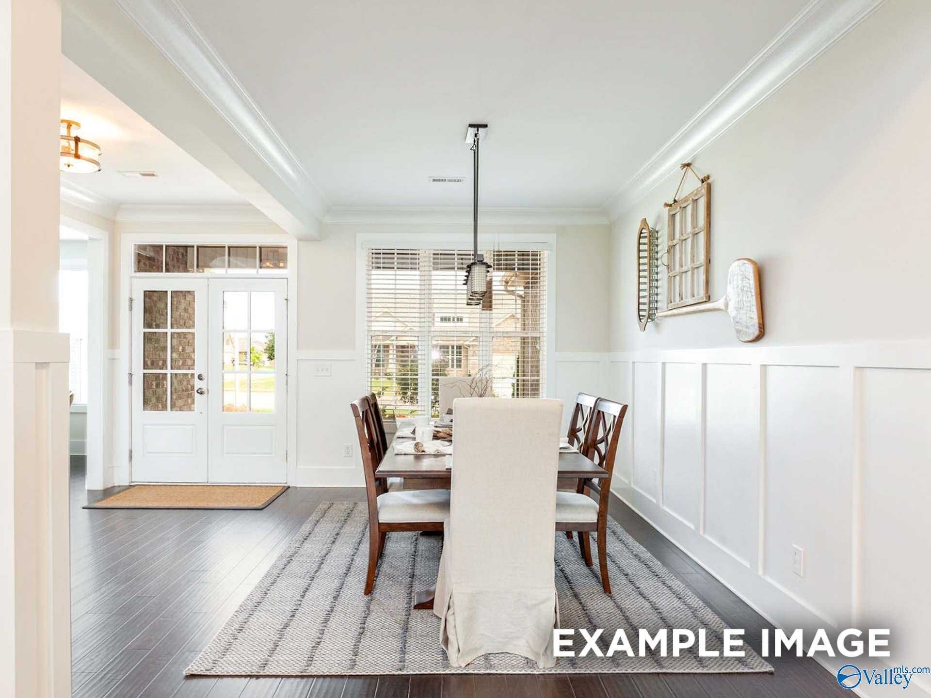 Elegant dining room featuring wooden table, upholstered chairs, chandelier, shiplap walls, and large windows in Davidson Homes The Finleigh, Meridianville