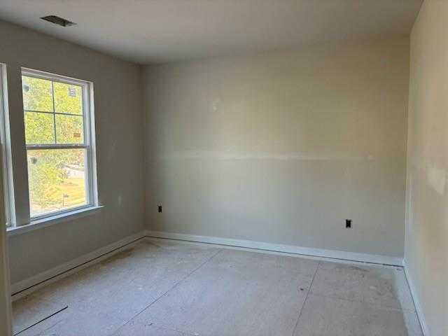 Bright empty bedroom with large windows, neutral walls, and hardwood subfloor in Davidson Homes The Hickory A, Riverwood, Dallas, Georgia