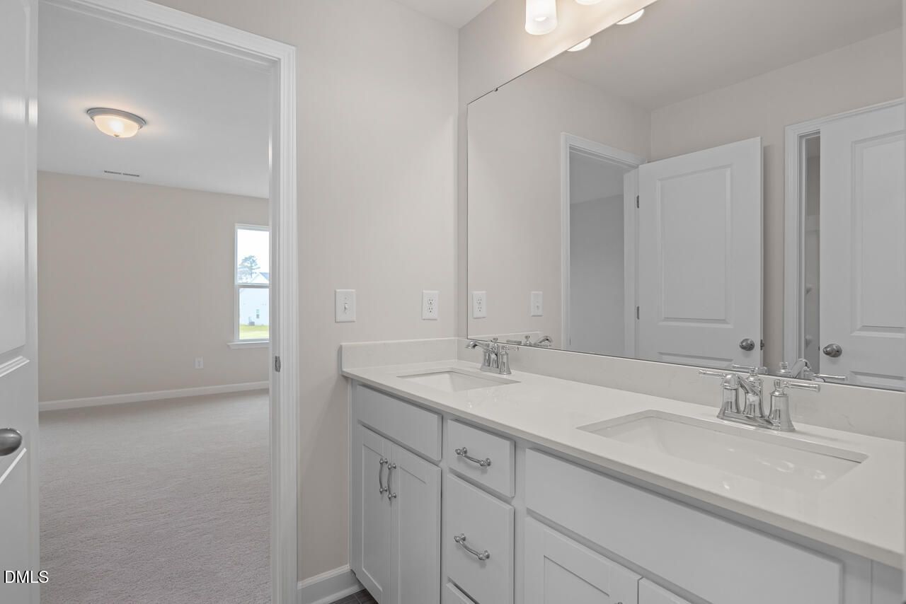 Elegant double vanity bathroom with white cabinets, quartz counters, and mirrors in Davidson Homes The Cypress D II, Angier, NC