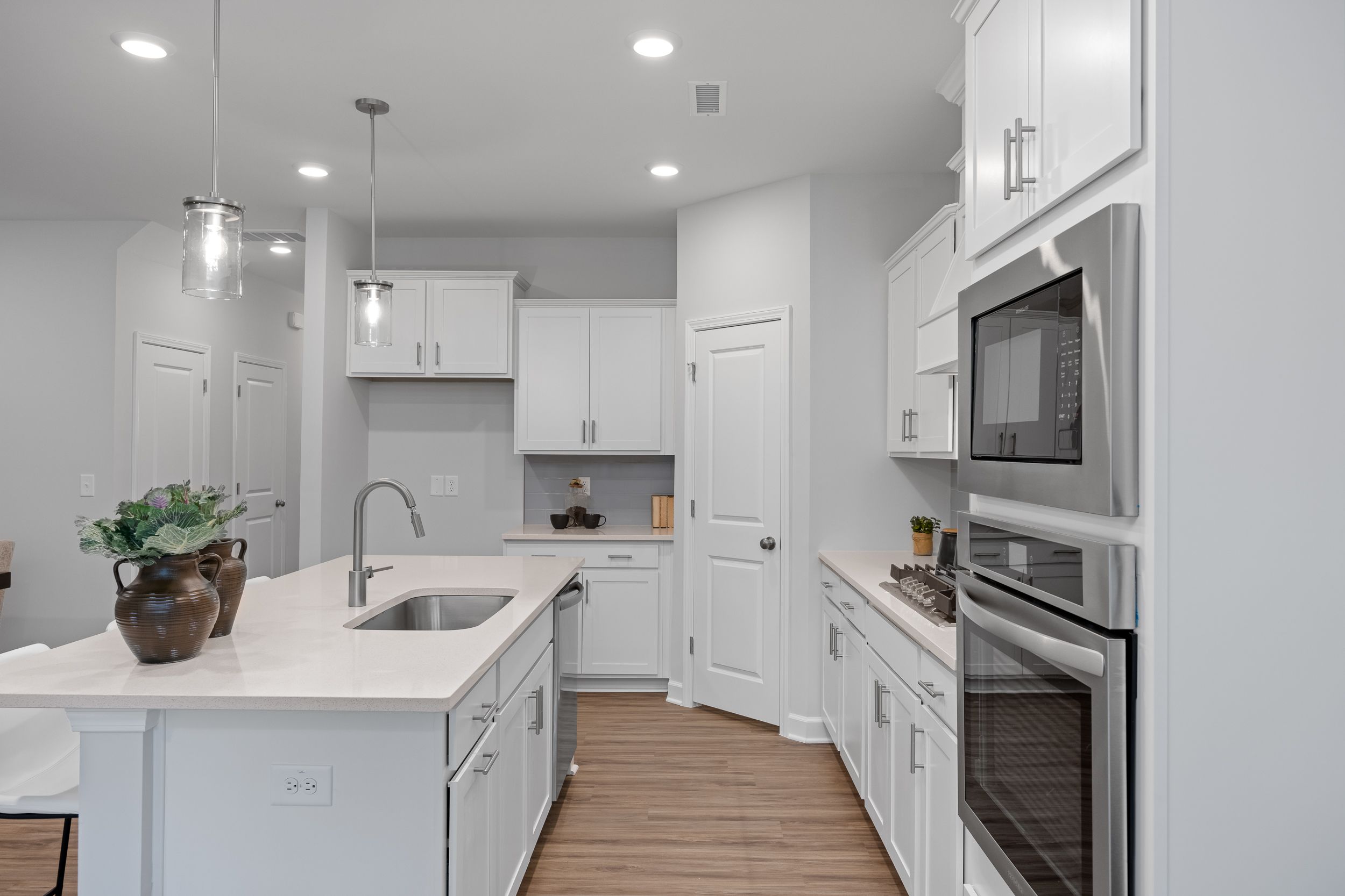 Modern kitchen in The Warren featuring white shaker cabinets, quartz countertops, a center island, and stainless appliances.
