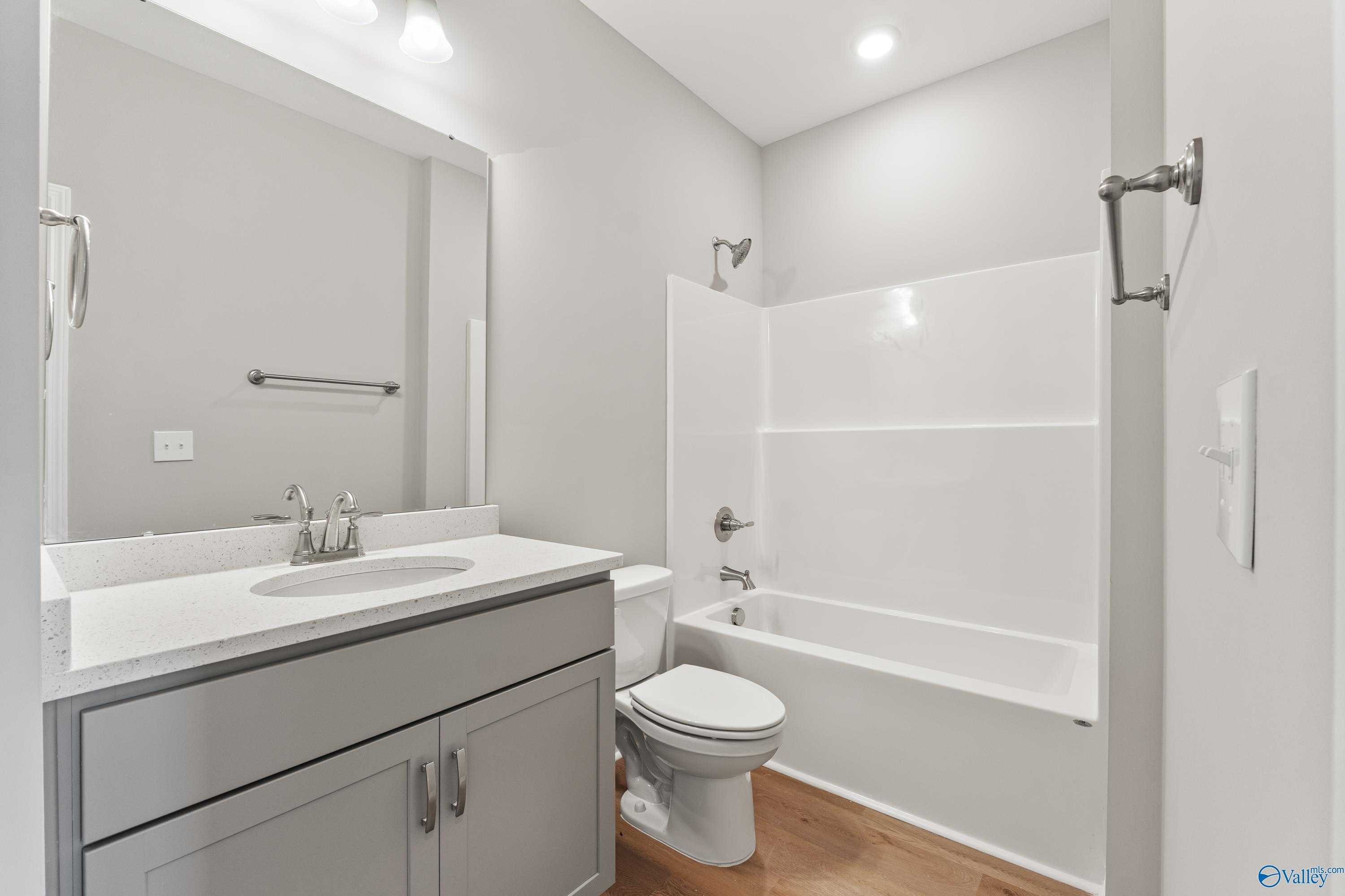 Modern bathroom with gray vanity, white tub shower combo, and toilet in Davidson Homes The Charm, Huntsville, Alabama