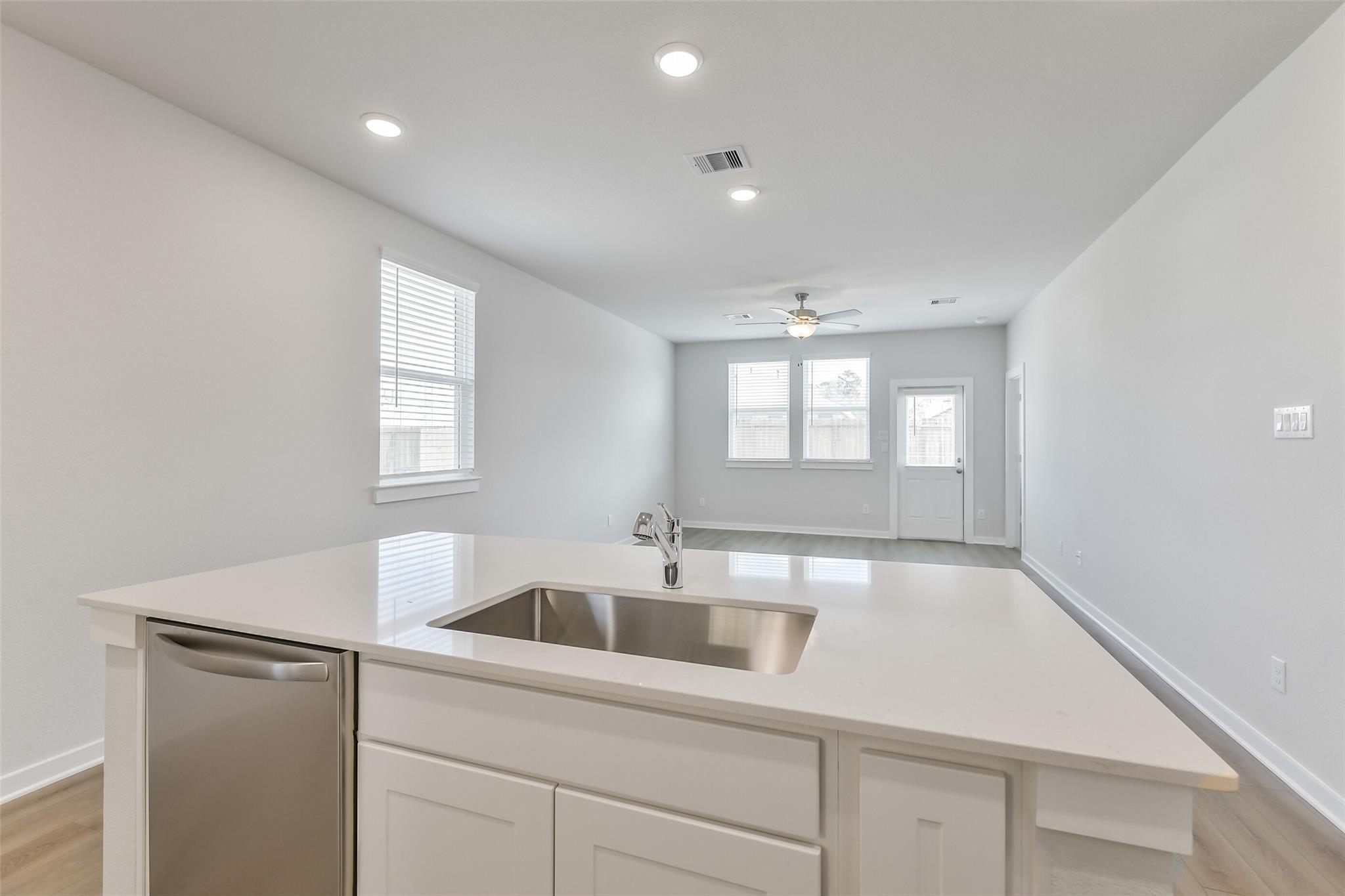 Modern open-concept kitchen with white island sink and stainless dishwasher in Davidson Homes The Colorado F, Cleveland Texas