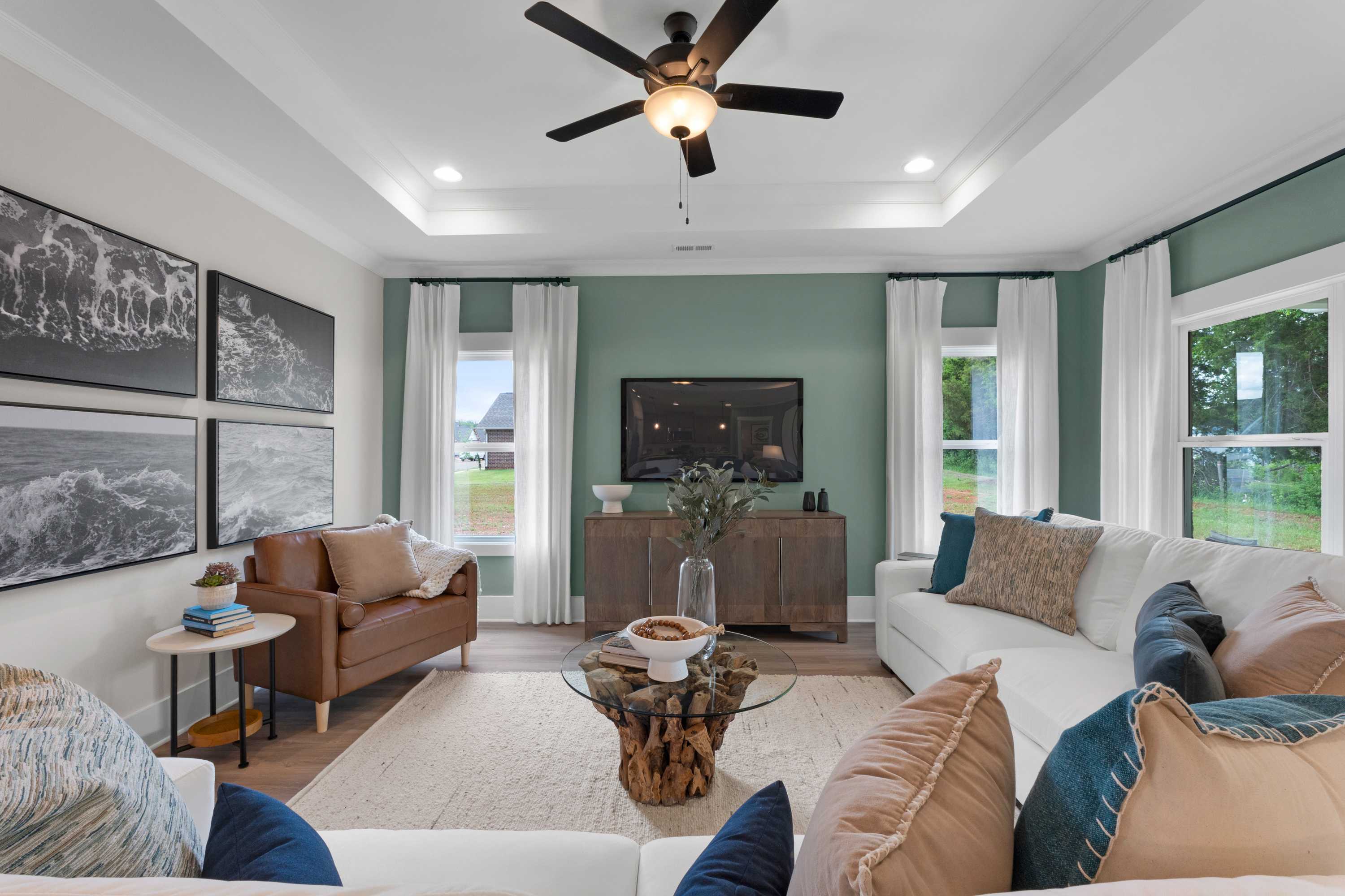 Cozy living room at Hollon Meadow in Decatur Alabama with white sectional sofa, ceiling fan, large windows, and modern decor