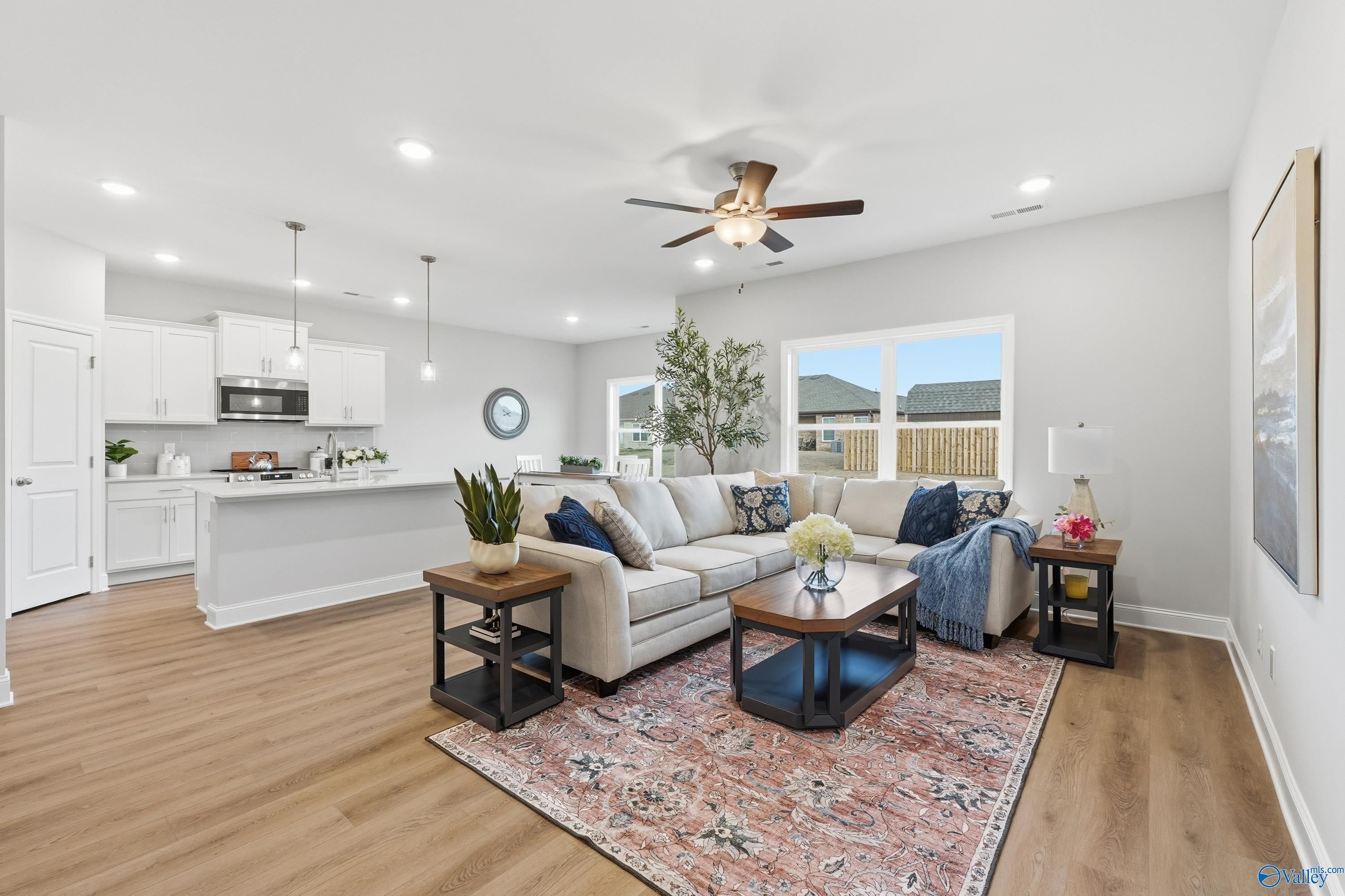 Cozy modern living room with gray sectional sofa, wooden coffee table, area rug, and open kitchen in Davidson Homes The Asheville, Toney, Alabama