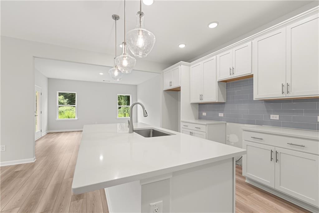 Modern white kitchen with quartz island and pendant lights in The Russell A floor plan at Cedar Farms in Winder, Georgia.
