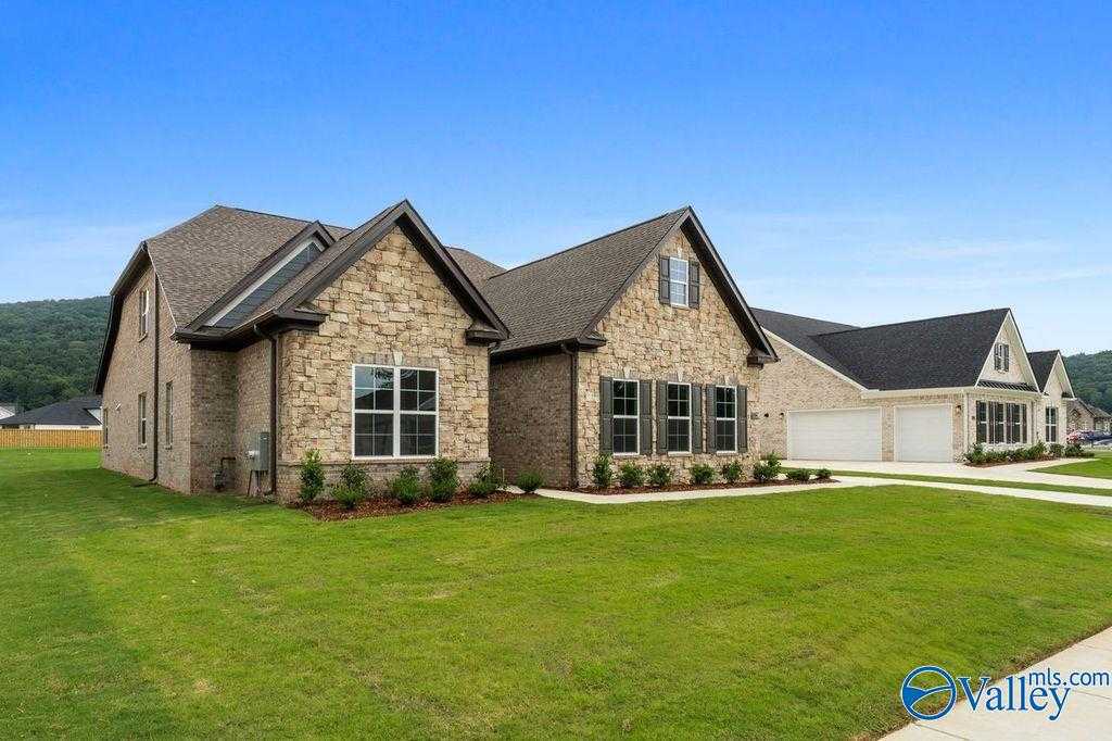 Modern 1.5-story Oxford home with brick-stone facade, 2-car garage, and lush green lawn in The Meadows at Hampton Cove, Owens Cross Roads, Alabama