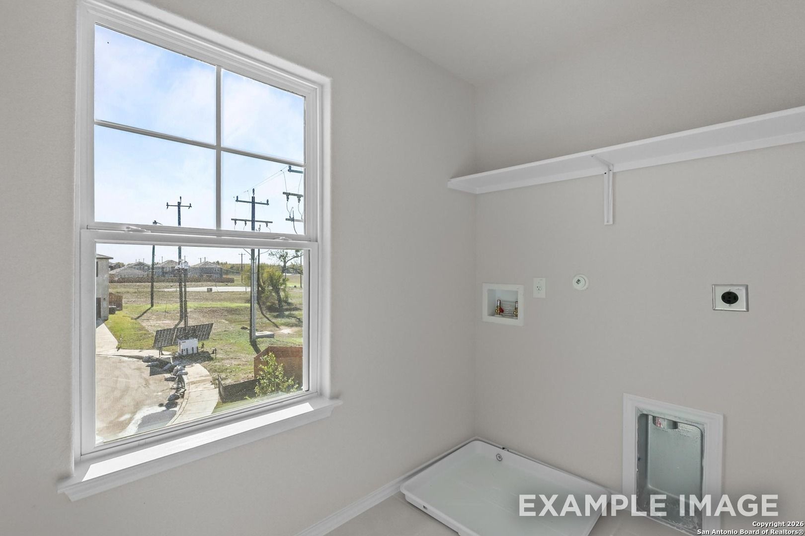 Bright laundry room with large window view of grassy yard and neighborhood in Davidson Homes Trinity B, San Antonio, Texas