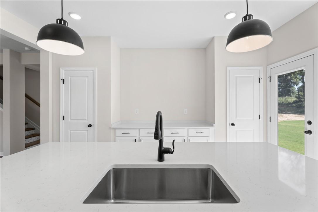 Modern kitchen island with quartz countertops and black pendant lighting in The Stella C home at Links Crossing, Auburn.