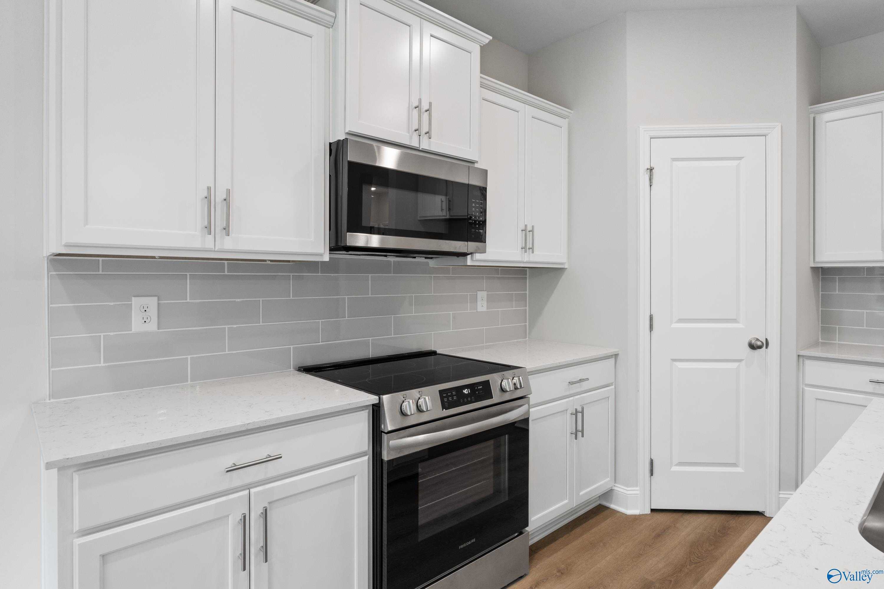 Modern white shaker kitchen with stainless oven, microwave, subway tile backsplash, quartz counters in Davidson Homes Asheville C, Huntsville AL