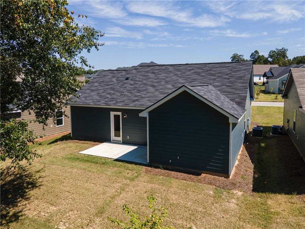 Rear view of The Washington 3-bedroom home with dark gray siding, covered patio, and grassy yard in Summer Vineyard, Phenix City, Alabama