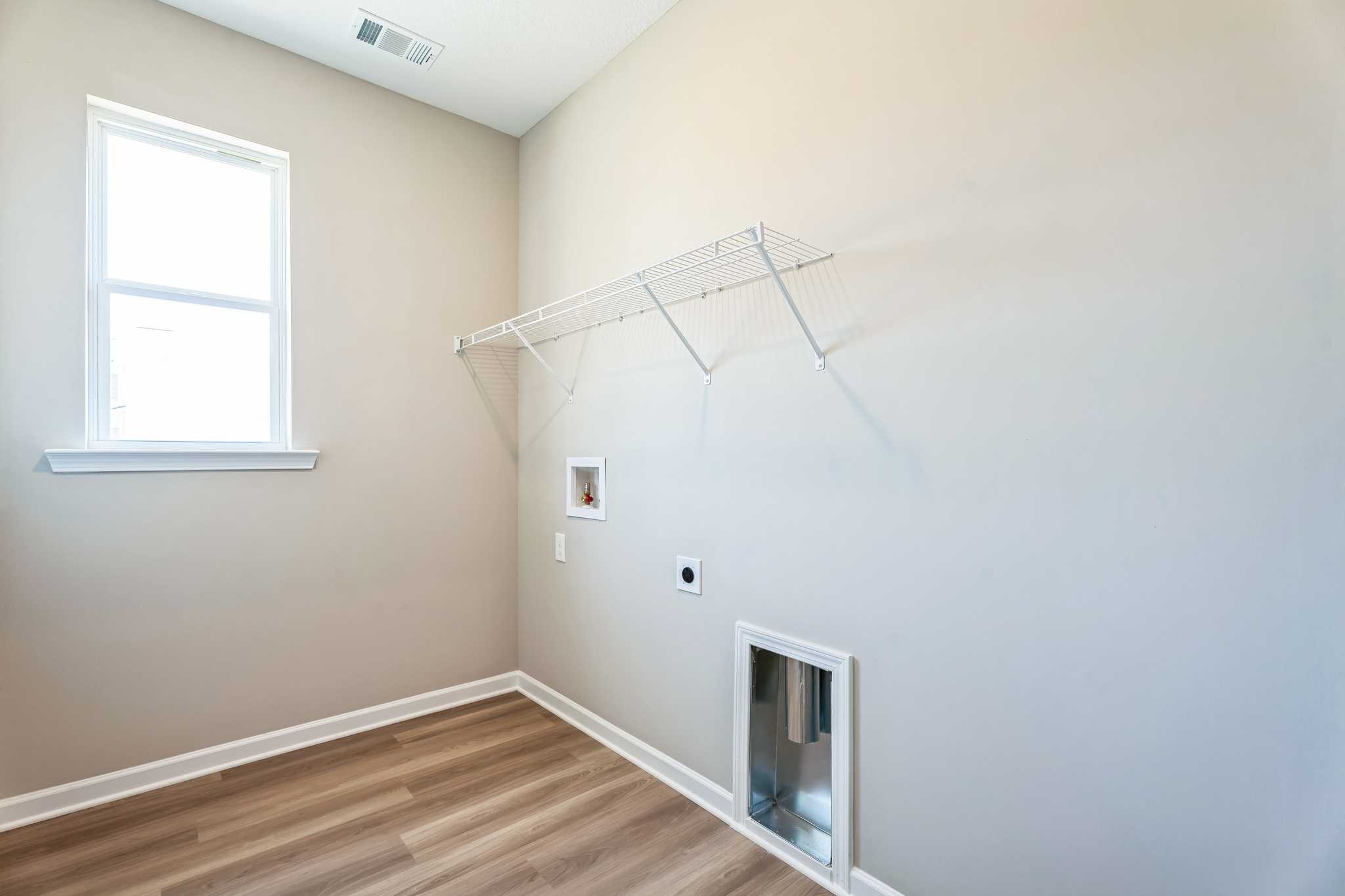 Laundry room at Anderson Lakes in Opelika Alabama with wire shelving utility sink pet door and hardwood floors