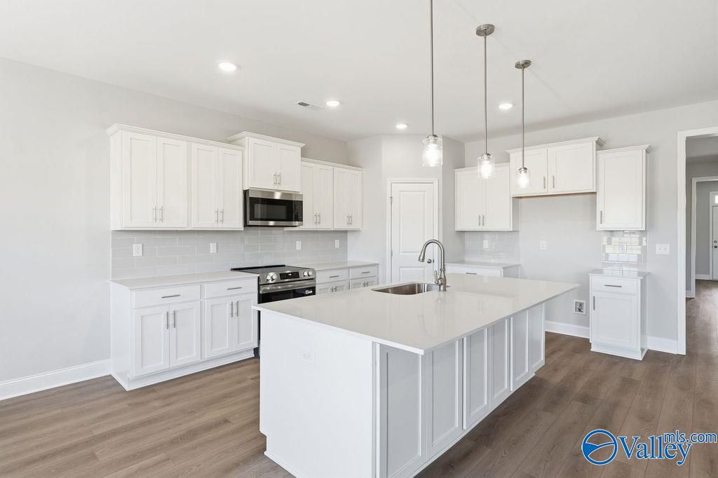 Modern white shaker kitchen with quartz island, stainless appliances, subway tile backsplash in The Harrison by Davidson Homes, Hartselle AL
