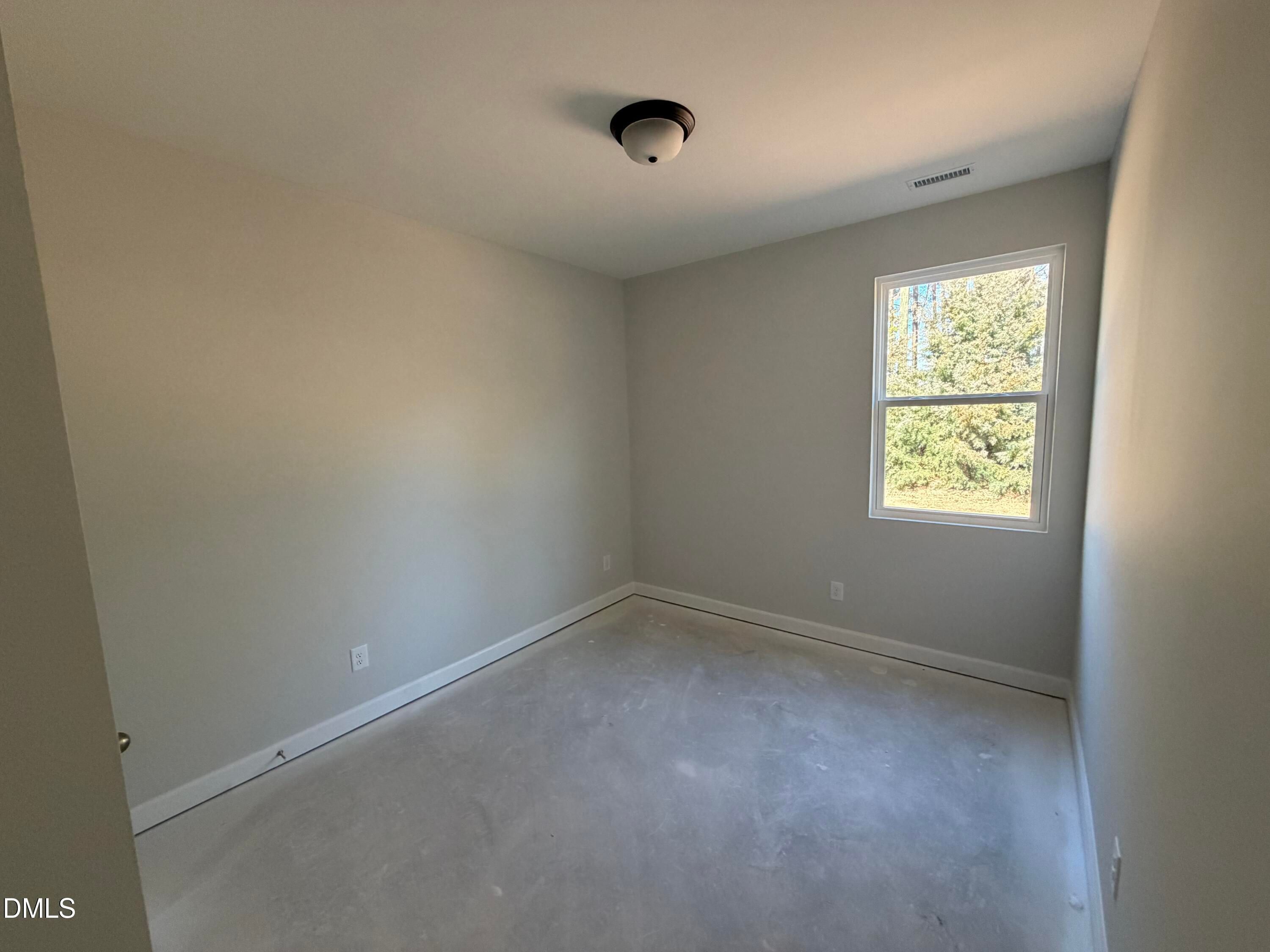 Bright empty secondary bedroom with neutral walls, ceiling fan, and large window in Davidson Homes The Carter C, Lillington, NC