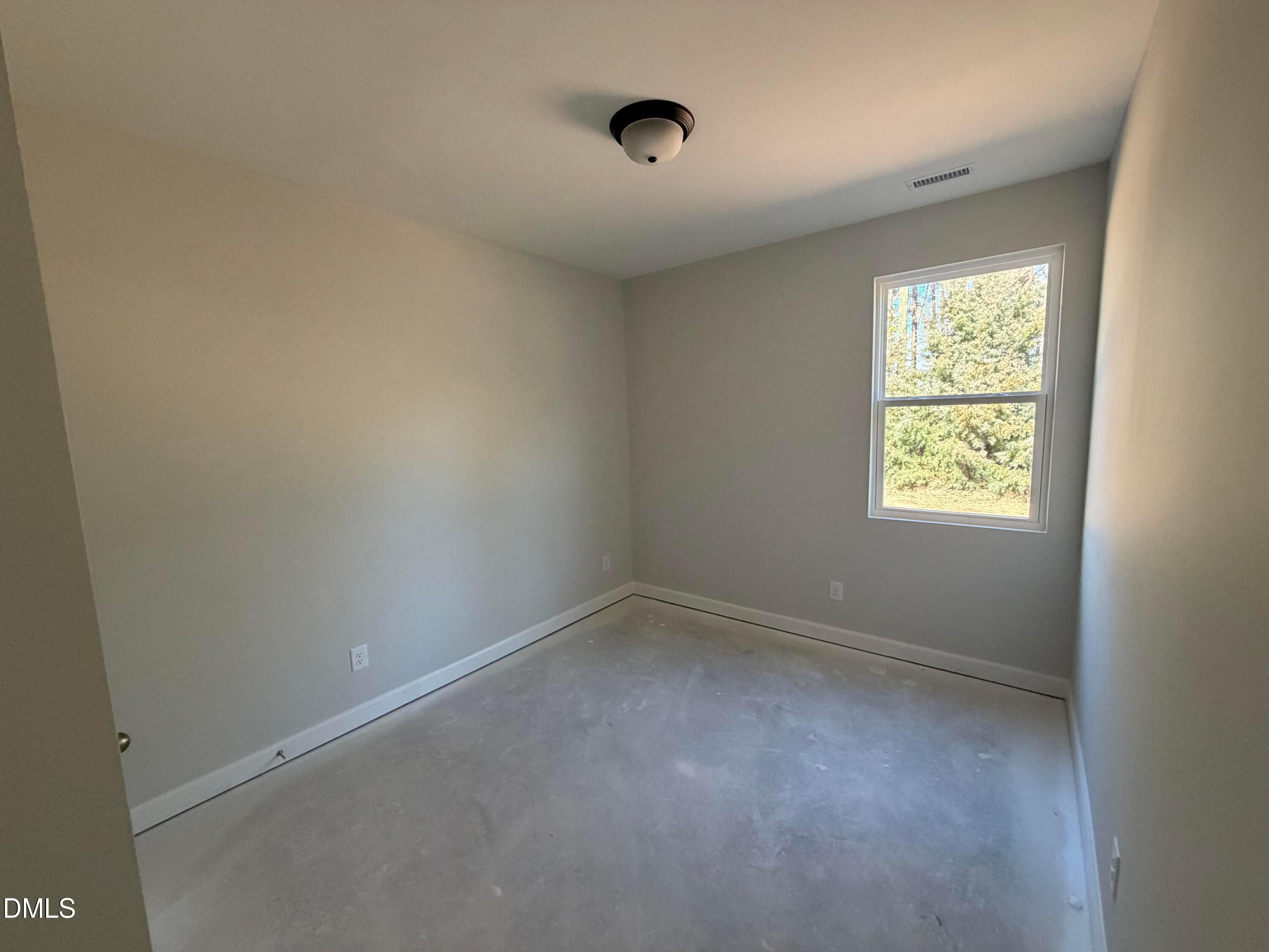 Bright empty secondary bedroom with neutral walls, ceiling fan, and large window in Davidson Homes The Carter C, Lillington, NC