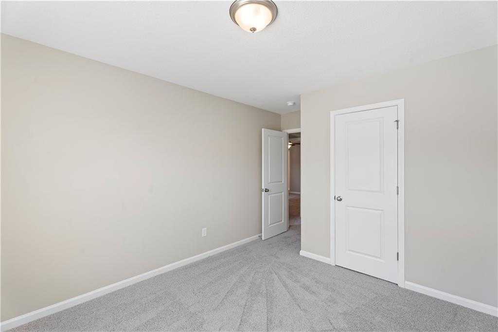 Cozy secondary bedroom with beige walls, gray carpet, and white doors to bath in Davidson Homes The Washington, Phenix City, Alabama