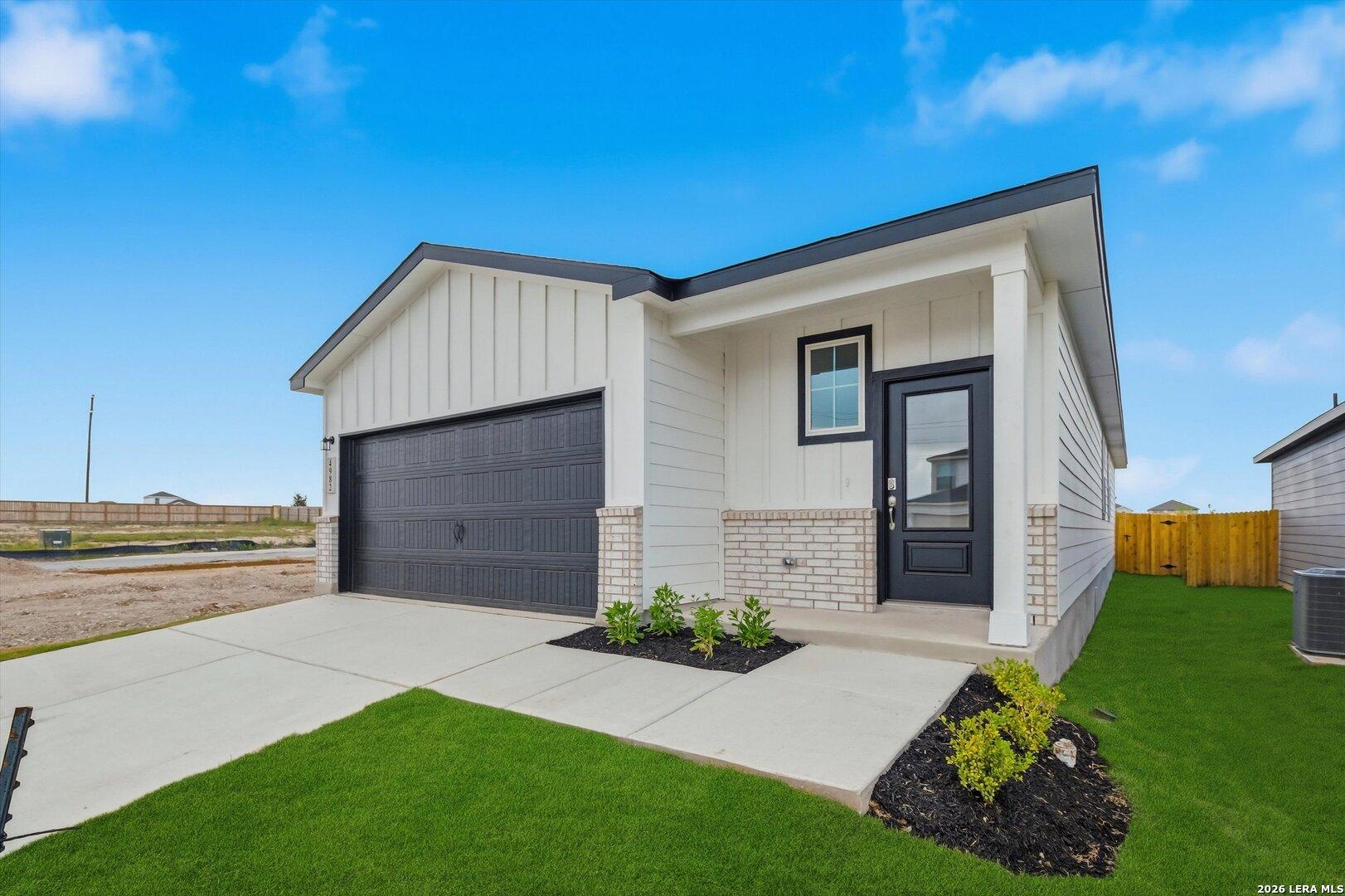 Modern white board-and-batten single-story home with 2-car garage, black door, and green lawn in Agave, San Antonio, Texas - Davidson Homes The Frio B