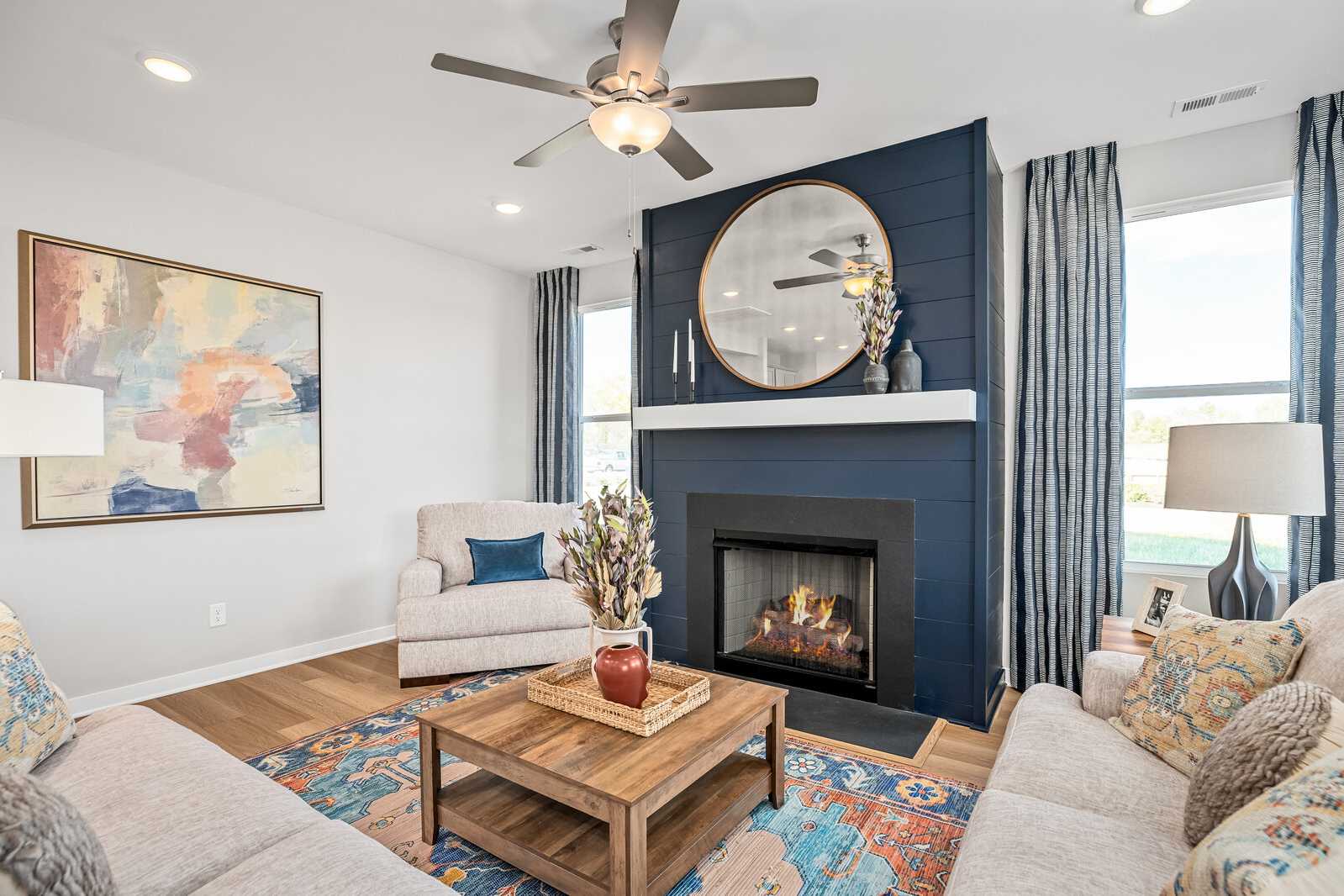 Cozy living room at Sage Farms in White House TN with navy accent wall, round mirror fireplace, plush beige sofas, and hardwood floors