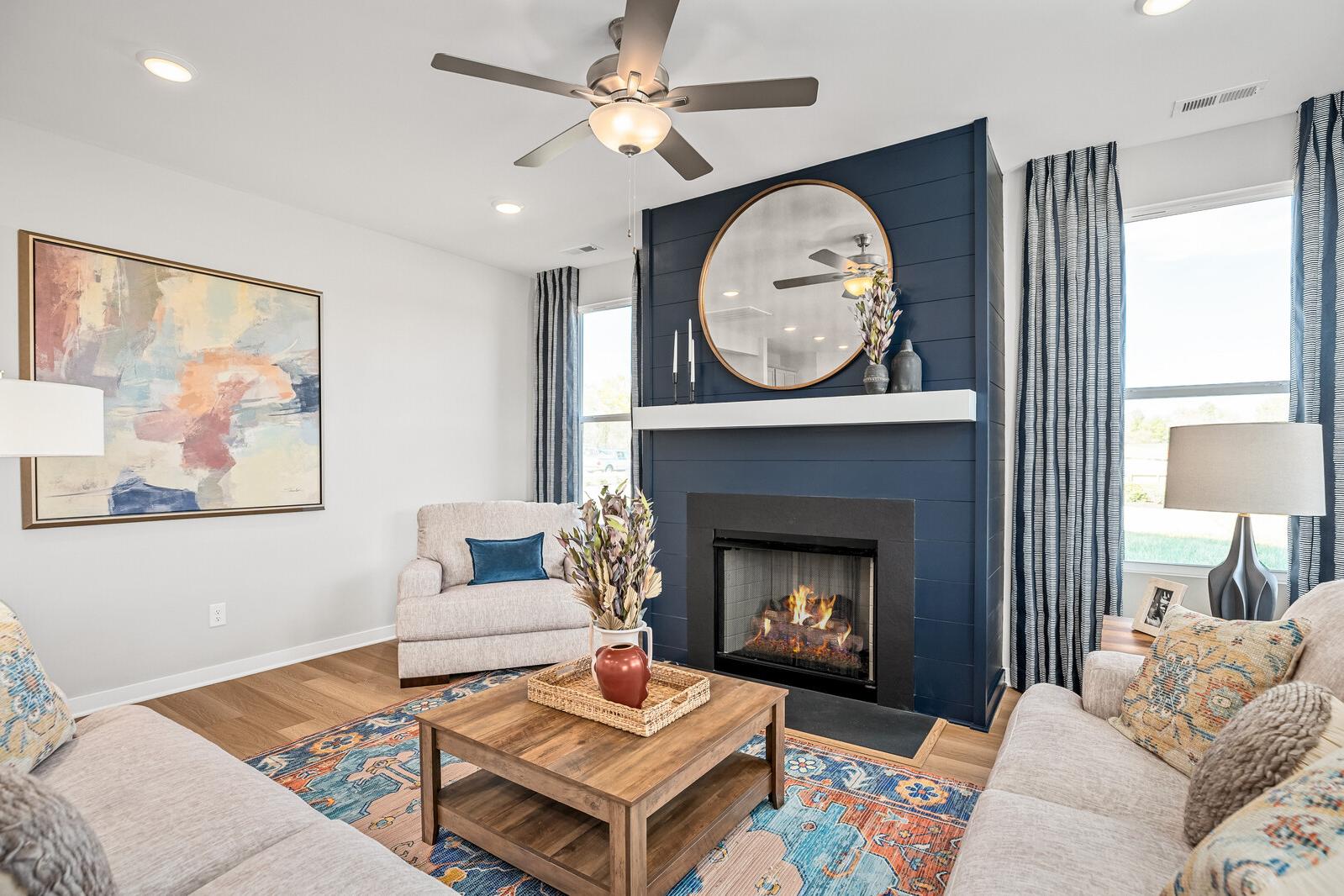 Cozy living room at Sage Farms in White House TN with navy accent wall, round mirror fireplace, plush beige sofas, and hardwood floors