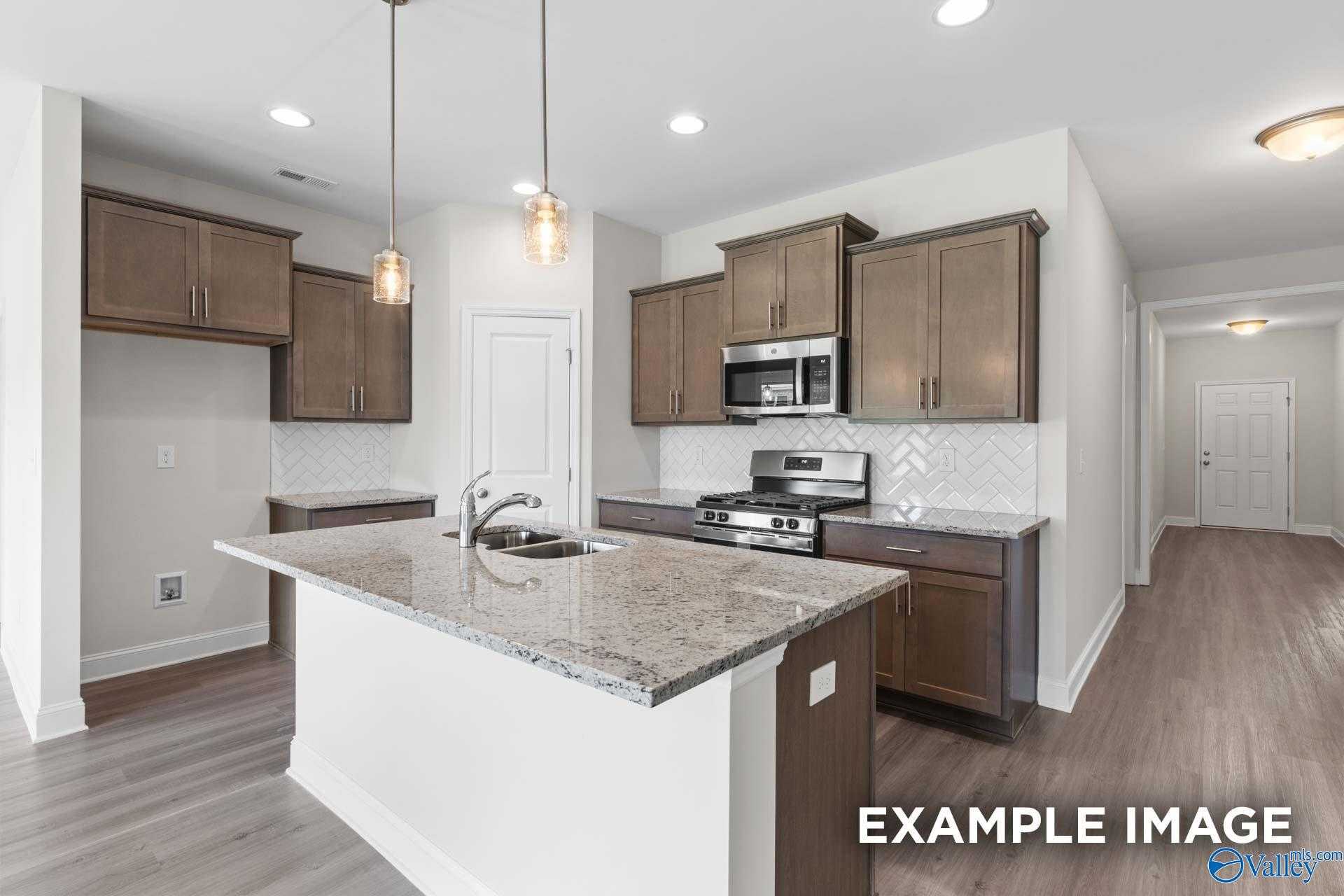 Modern kitchen with granite island, shaker cabinets, stainless appliances in Davidson Homes The Daphne D, Arab, Alabama