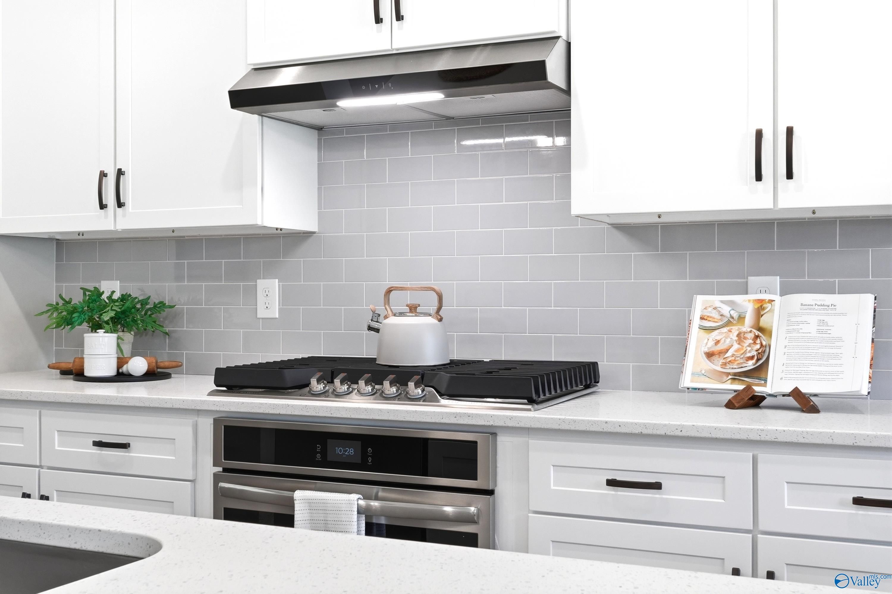 Modern kitchen with white cabinets, gray subway tile backsplash, and stainless steel gas range in The Dorado, Huntsville.