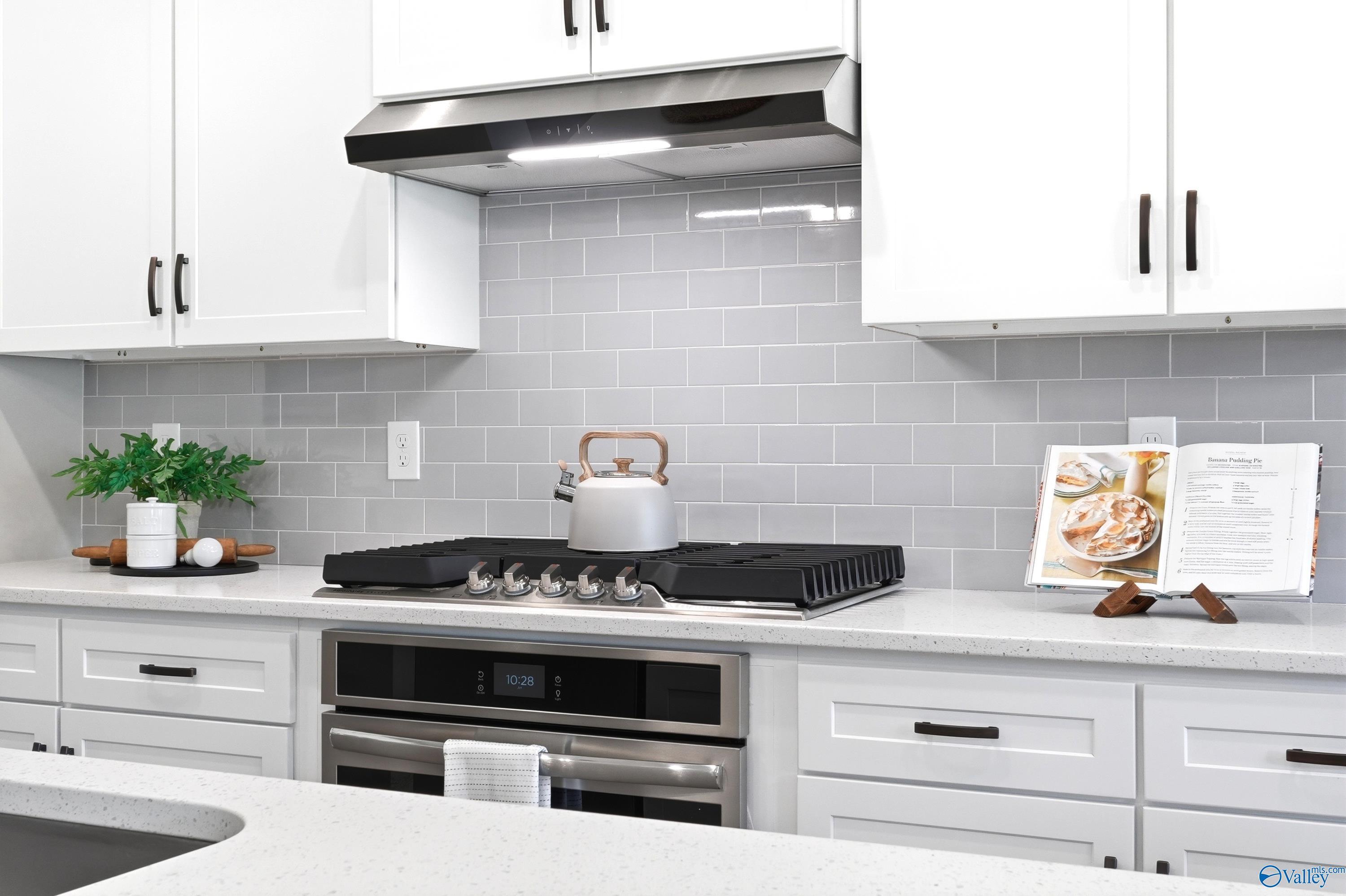 Modern kitchen with white cabinets, gray subway tile backsplash, and stainless steel gas range in The Dorado, Huntsville.