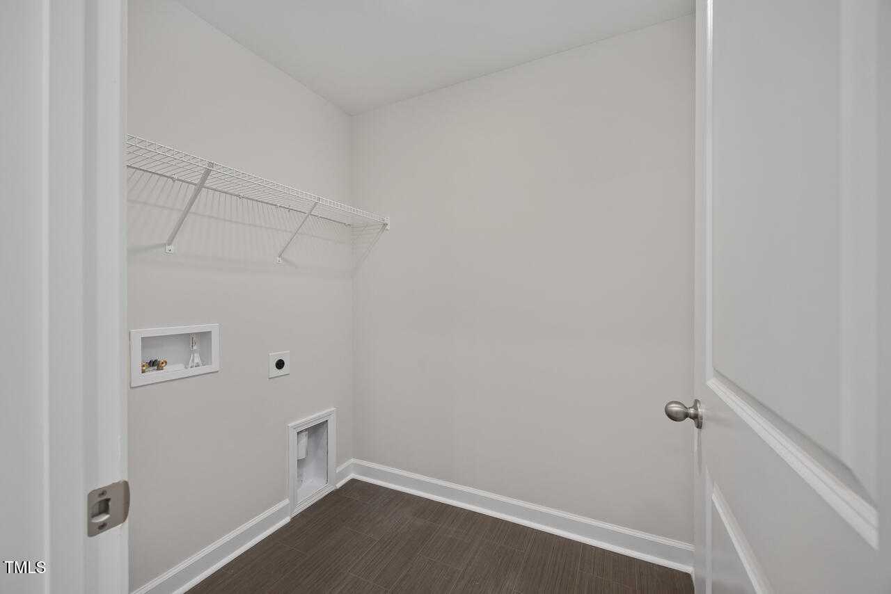 Functional laundry room with wire shelving, washer/dryer hookups, and floor drain in Davidson Homes The Graham, Fuquay-Varina, NC