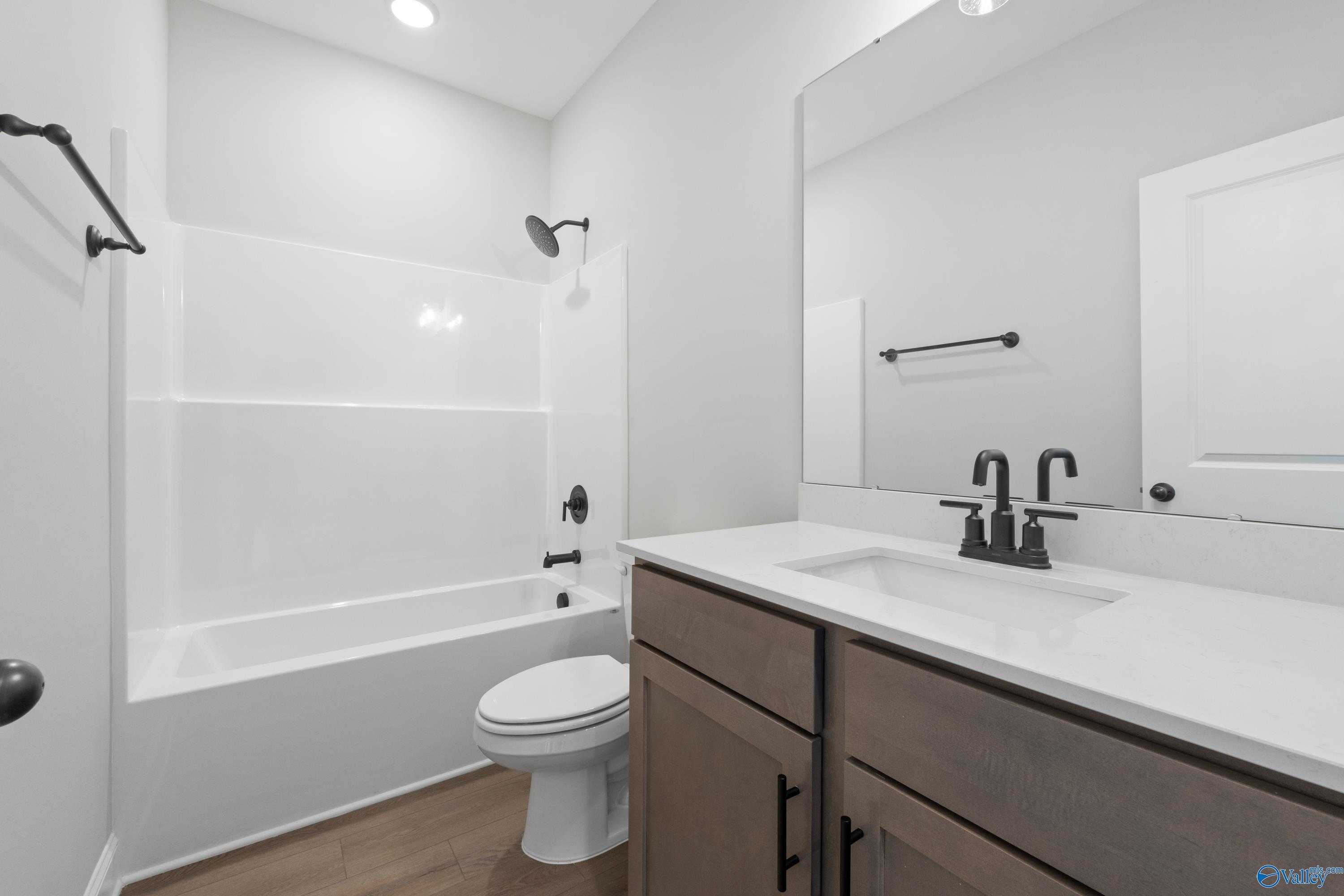Modern guest bathroom with white subway tile tub-shower combo, black fixtures, and shaker vanity in Davidson Homes The Franklin C, Hazel Green, AL