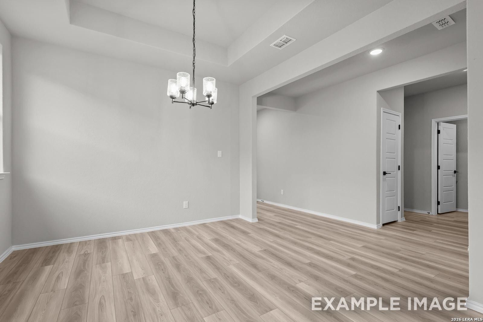 Bright dining area with tray ceiling and modern chandelier in The Glenwood E floor plan, Royal Crest, San Antonio home.