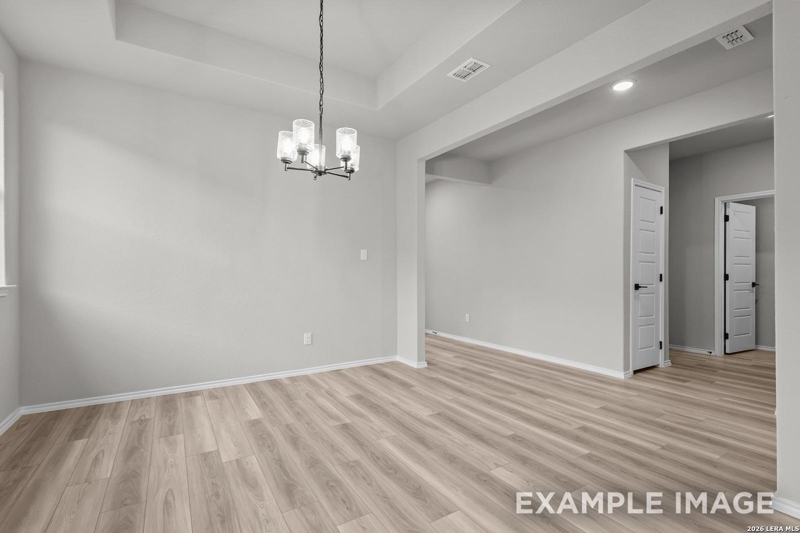 Bright dining area with tray ceiling and modern chandelier in The Glenwood E floor plan, Royal Crest, San Antonio home.