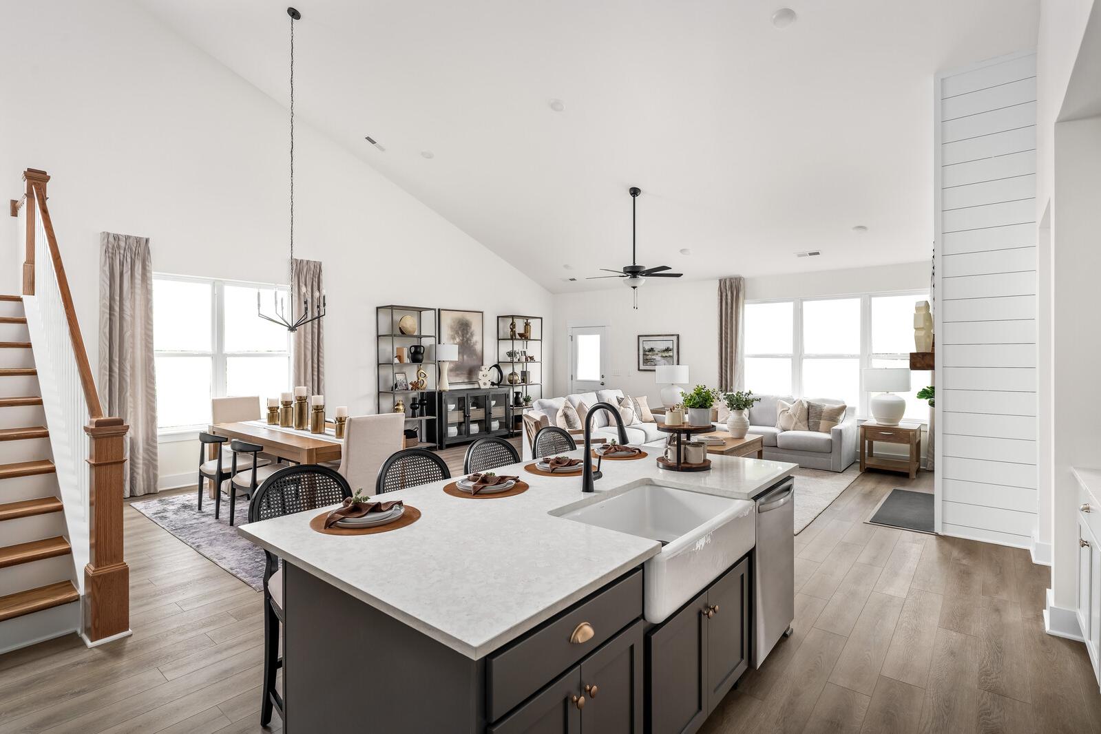 Open-concept kitchen and living room at Woods Crossing in Gallatin TN with quartz island, farmhouse sink, hardwood floors, and vaulted ceilings