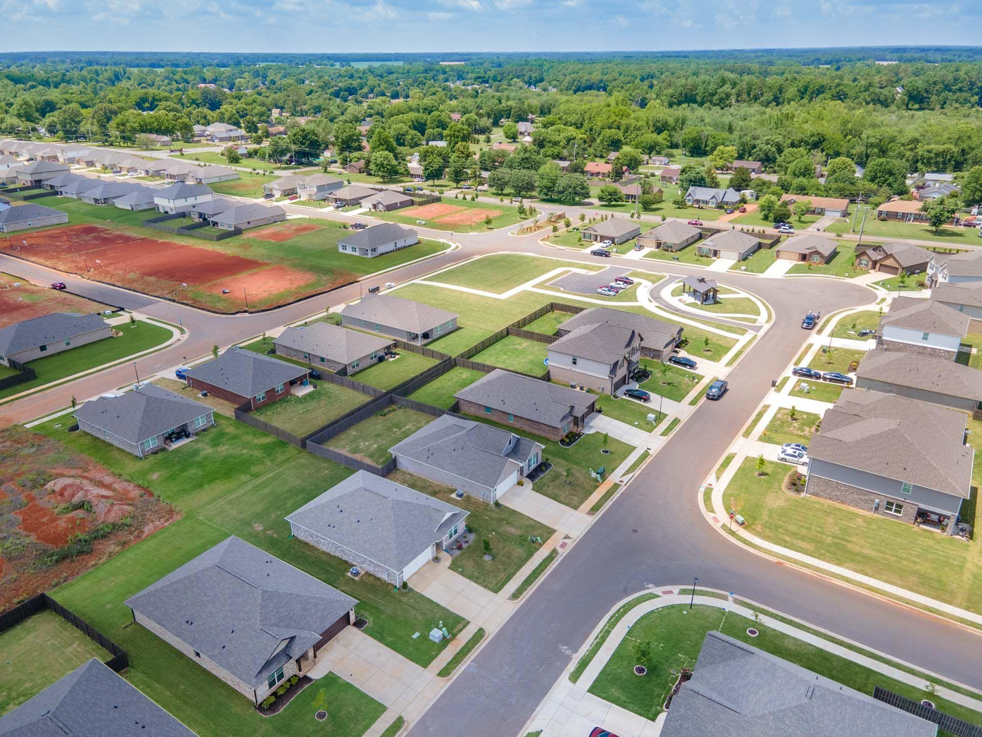 Aerial view of Clearview neighborhood in Hazel Green Alabama featuring new Davidson Homes, tree-lined streets, green lawns, and red clay tennis courts