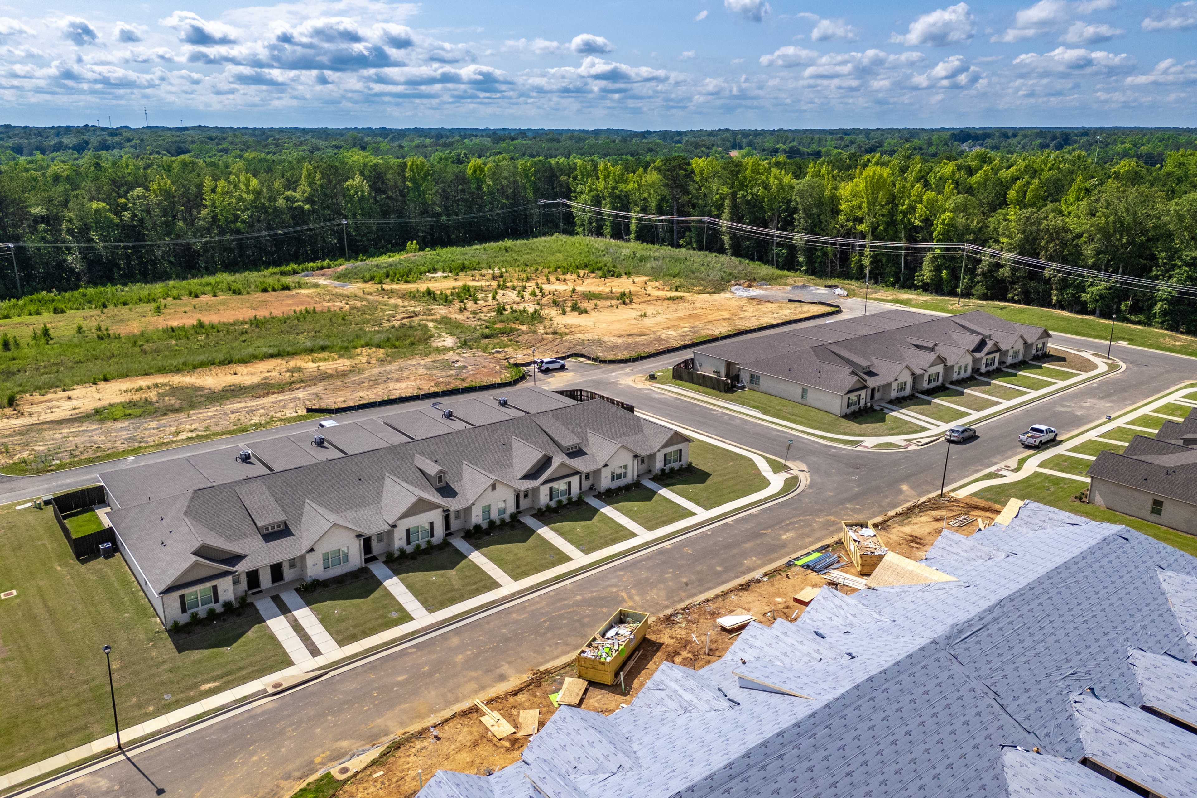 Townhomes under construction at Cain Park in Hartselle Alabama with gabled roofs and surrounding woods