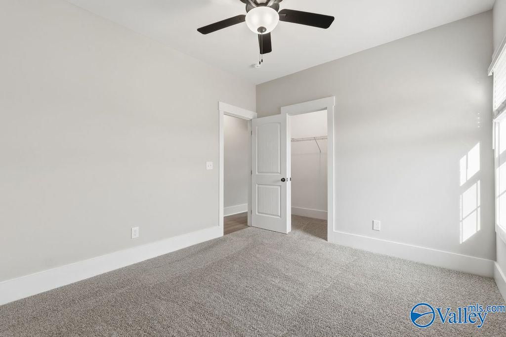 Spacious bedroom with ceiling fan, open walk-in closet, gray walls, and carpet in Davidson Homes The Rockford, Hartselle Alabama
