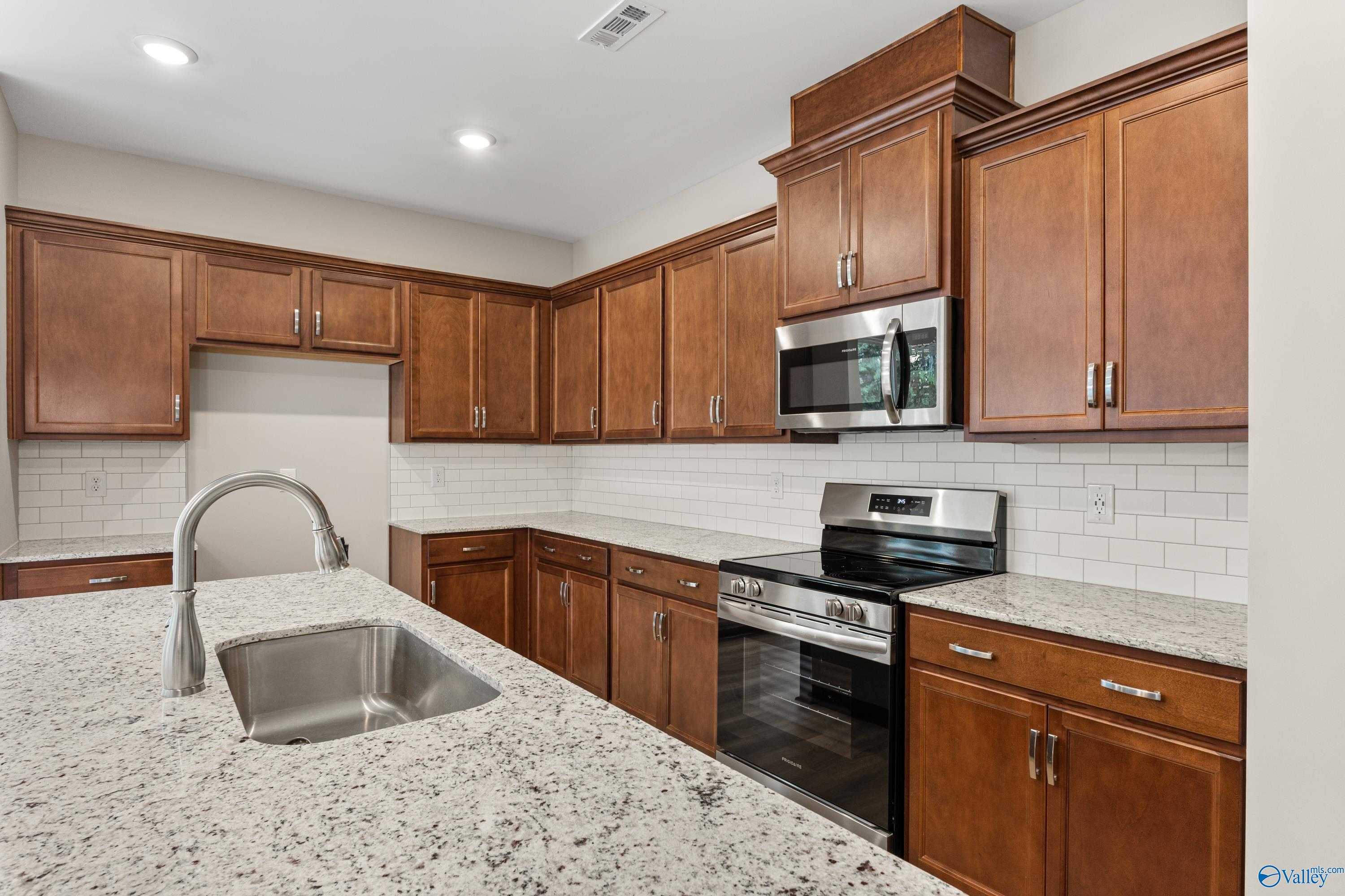 Modern kitchen with shaker cabinets, granite counters, subway tile backsplash, stainless appliances in Davidson Homes The Aurora, Fayetteville, TN