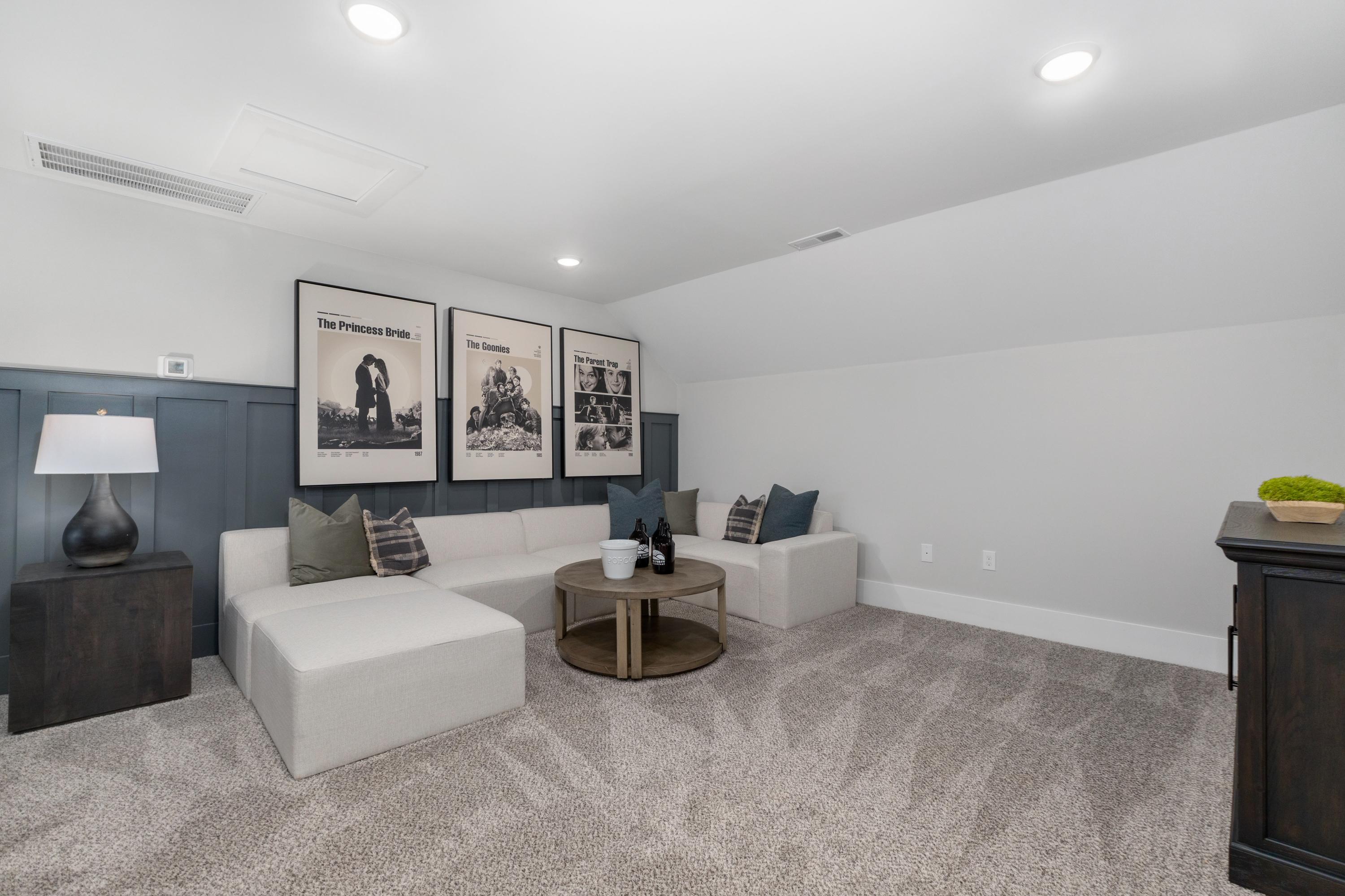 Cozy bonus room at Kendall Farms in Toney Alabama with white sectional sofa, shiplap wall, framed artwork, and carpeted floor