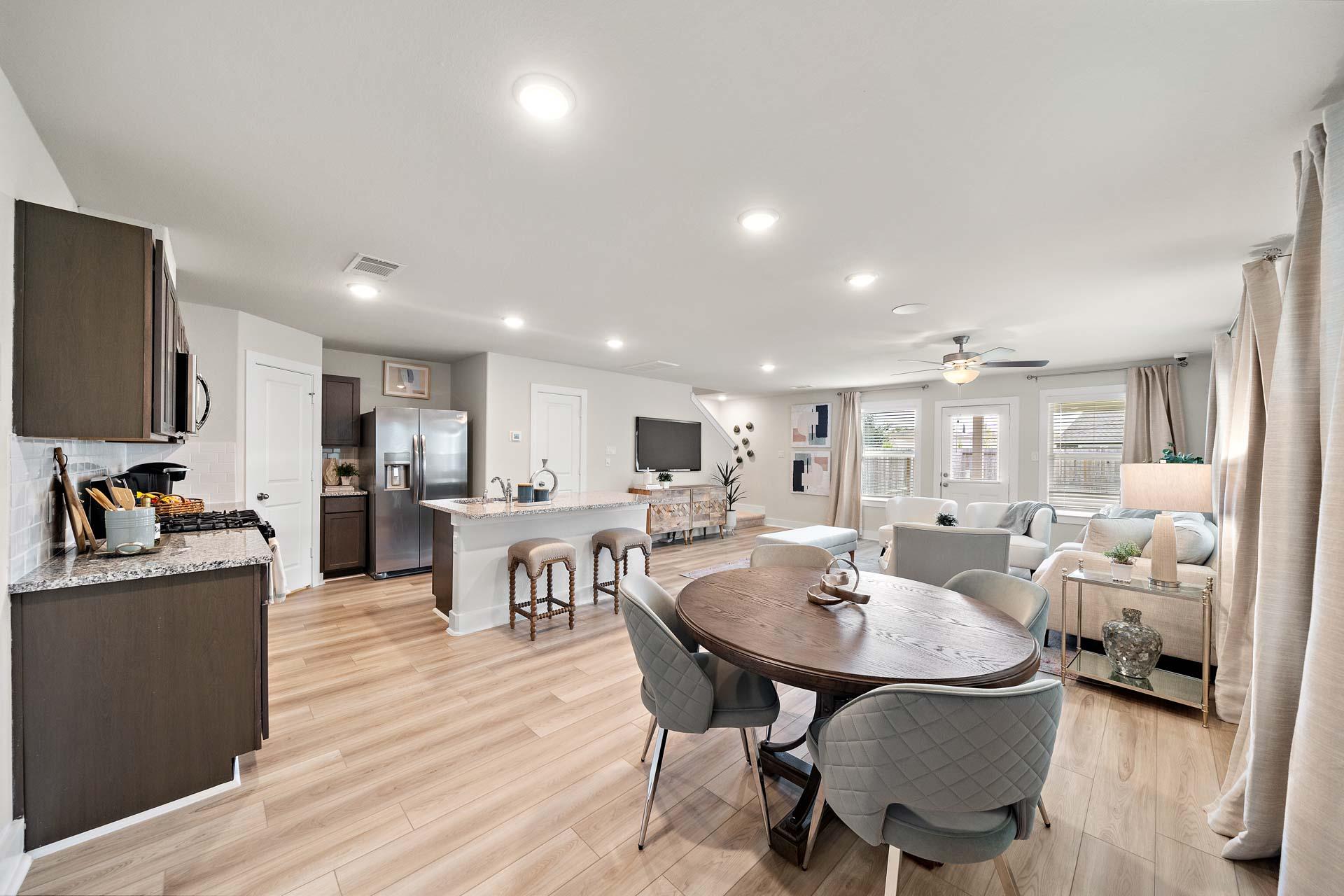 Spacious open-concept kitchen and living area at Haven at Kieth Harrow in Cypress Texas with hardwood floors island bar and dining table