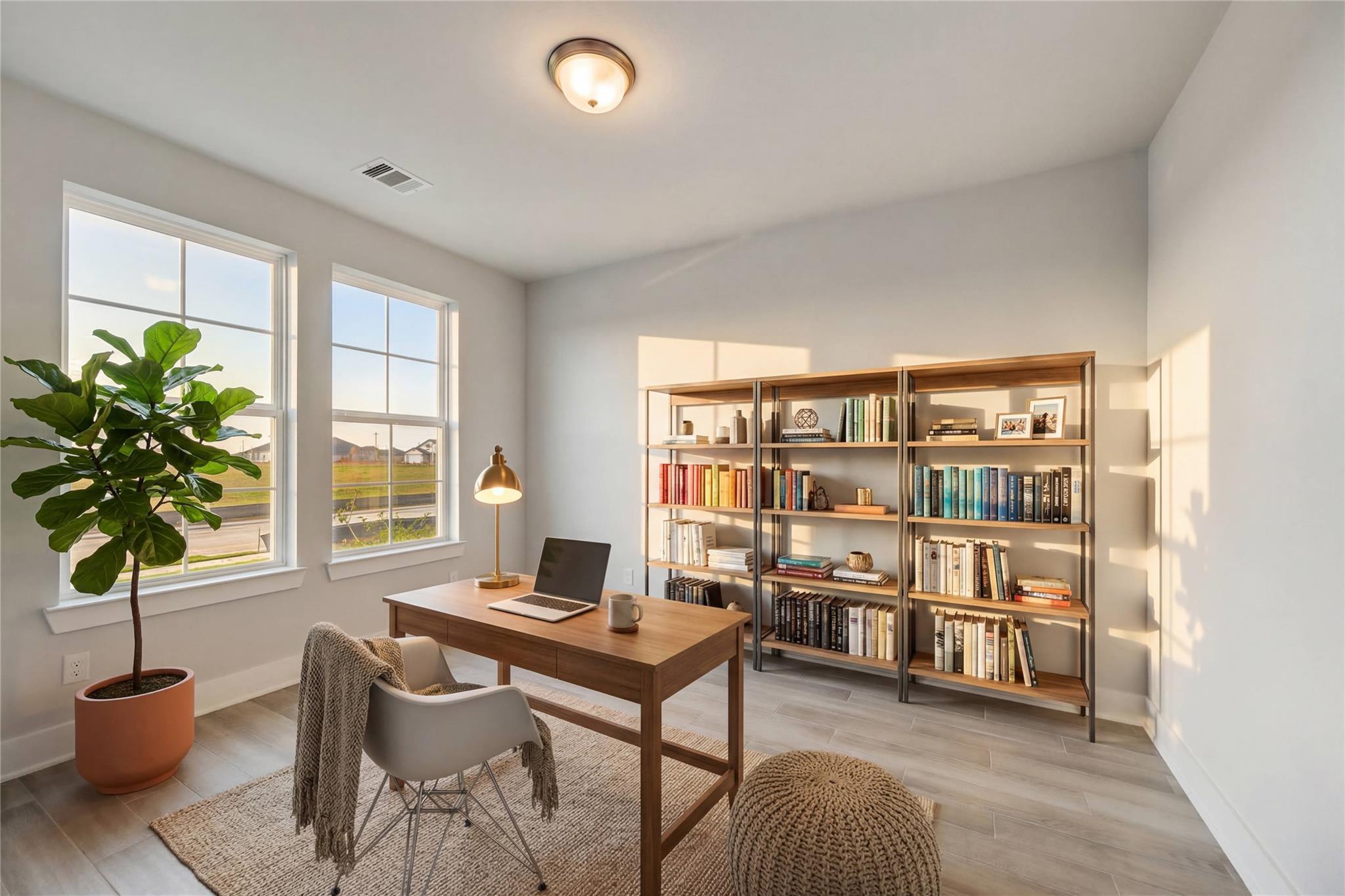 Modern home office with wooden desk, laptop, bookshelves, fiddle leaf plant, and large windows in Davidson Homes The Philip A, Lago Mar, Texas City