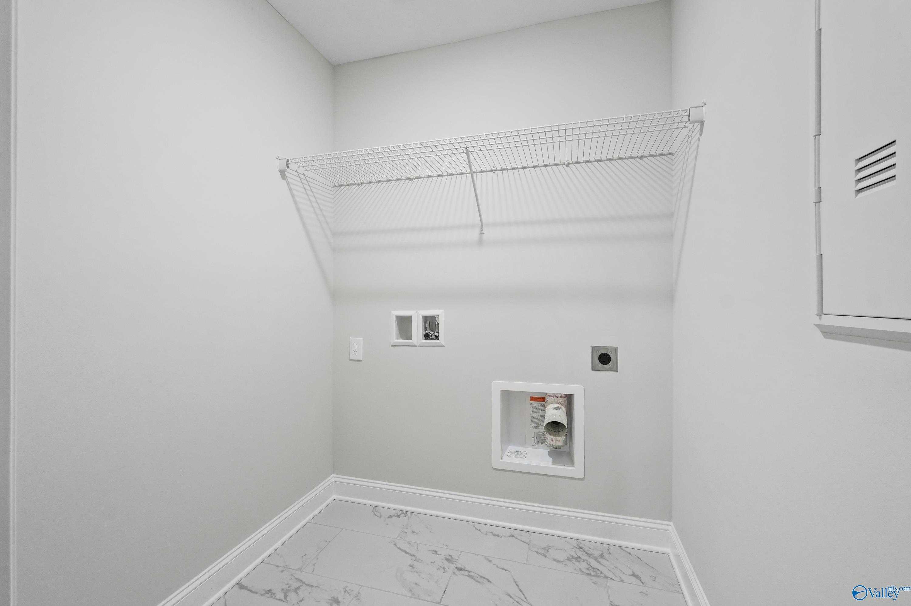Modern laundry room with wire shelving, washer-dryer hookups, and gray marble tile floor in Davidson Homes The Camden, Huntsville AL