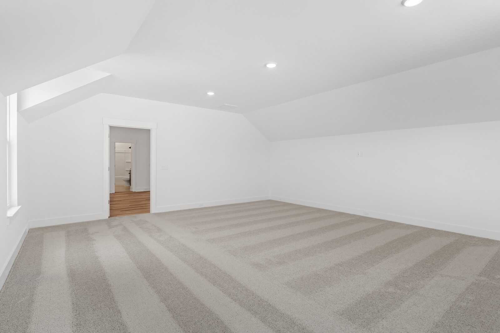 Spacious empty bedroom with vaulted ceiling, recessed lights, and beige carpet in Davidson Homes The Hathaway, Murfreesboro, TN