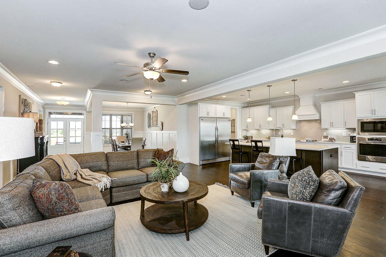 Spacious open-concept living room and kitchen in The Finleigh with gray sectional sofa, white cabinetry, island, and ceiling fans