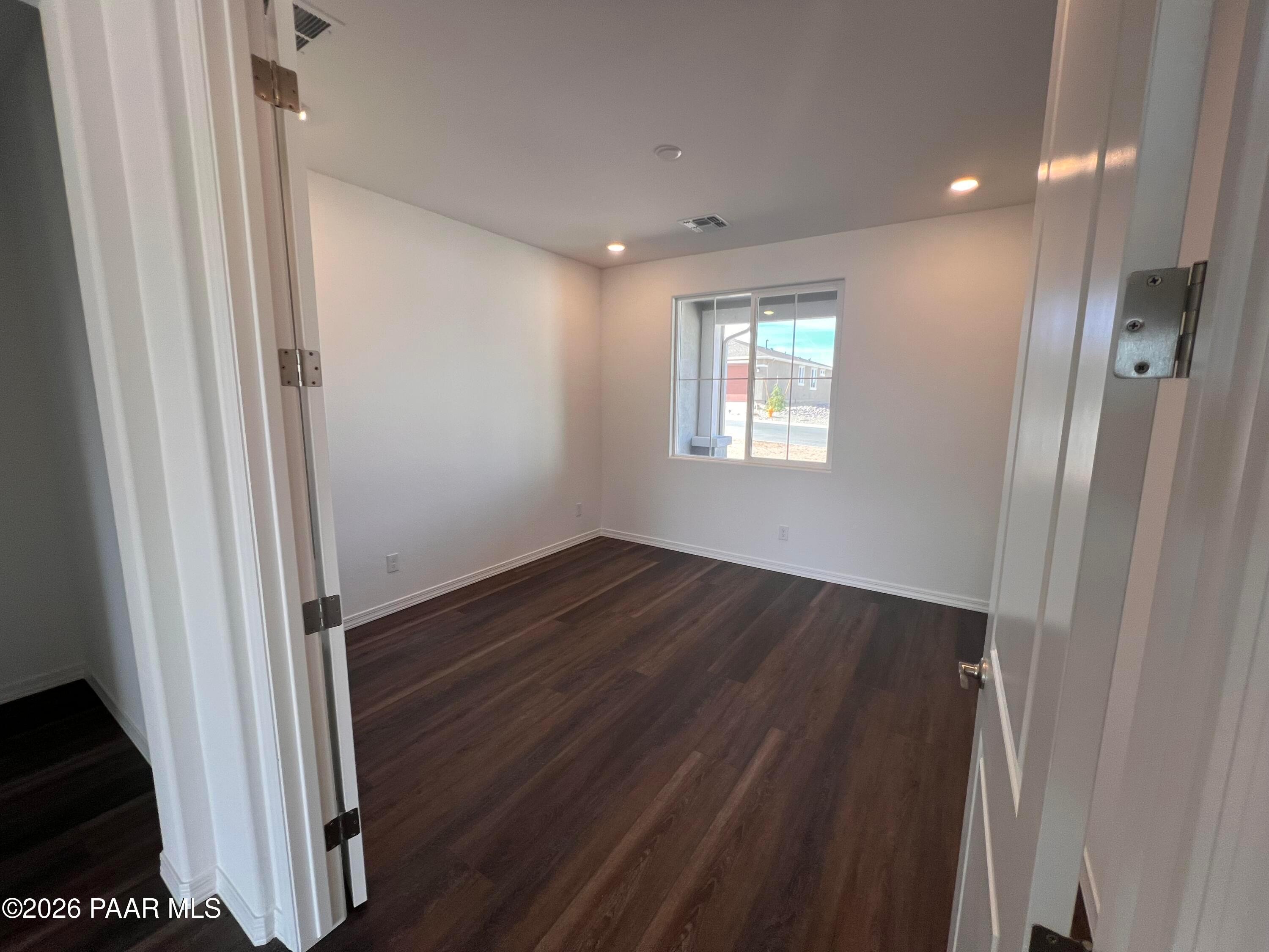 Spacious empty bedroom with luxury vinyl plank flooring, white walls, and large window in Davidson Homes The Monarch A, Prescott AZ